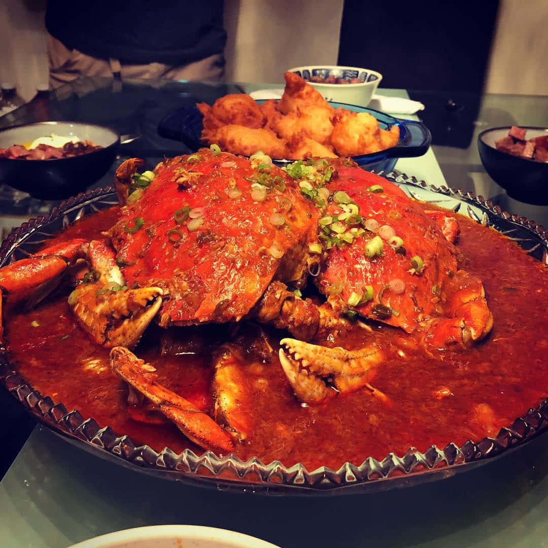 Crab 桌布 壁紙 — 一盤熱騰騰的辣蟹，配上濃郁的紅醬，撒上蔥花，放在餐桌中央。