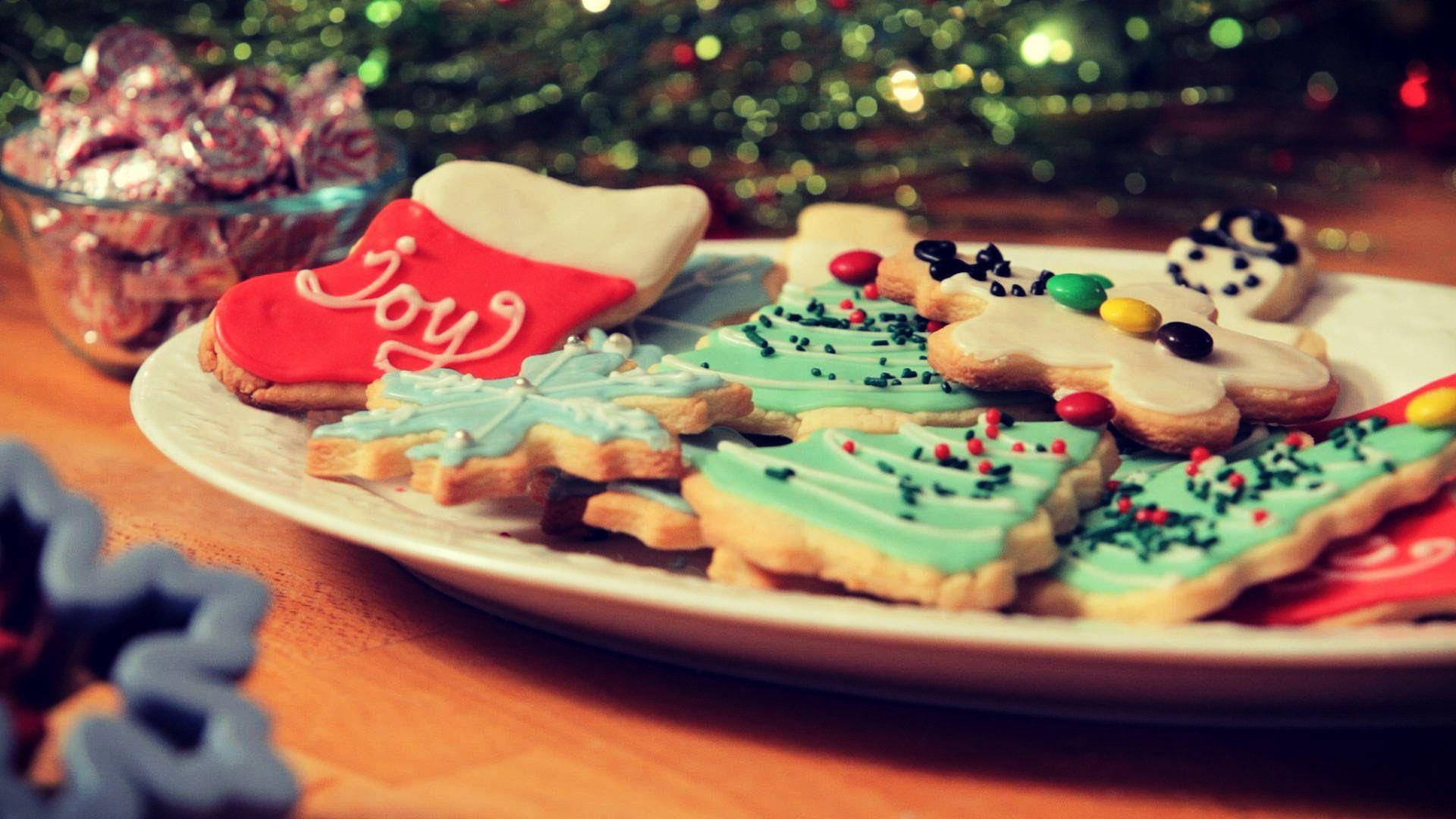 Christmas Cookies 桌布 壁紙 — 一盤節日聖誕餅乾，形狀有樹木、雪花和襪子，裝飾有糖霜、糖粒和糖果。