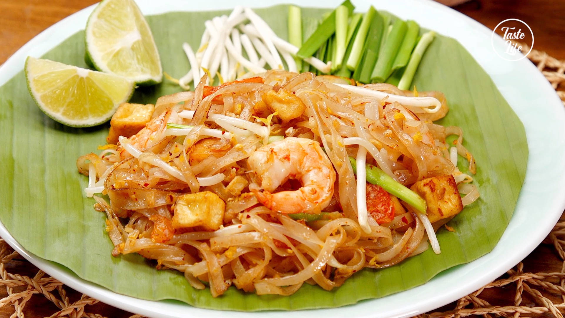 thai 桌布 壁紙 — 一盤色彩繽紛的泰式炒河粉，配上蝦仁、豆腐、豆芽和青檸角，放在香蕉葉上享用。