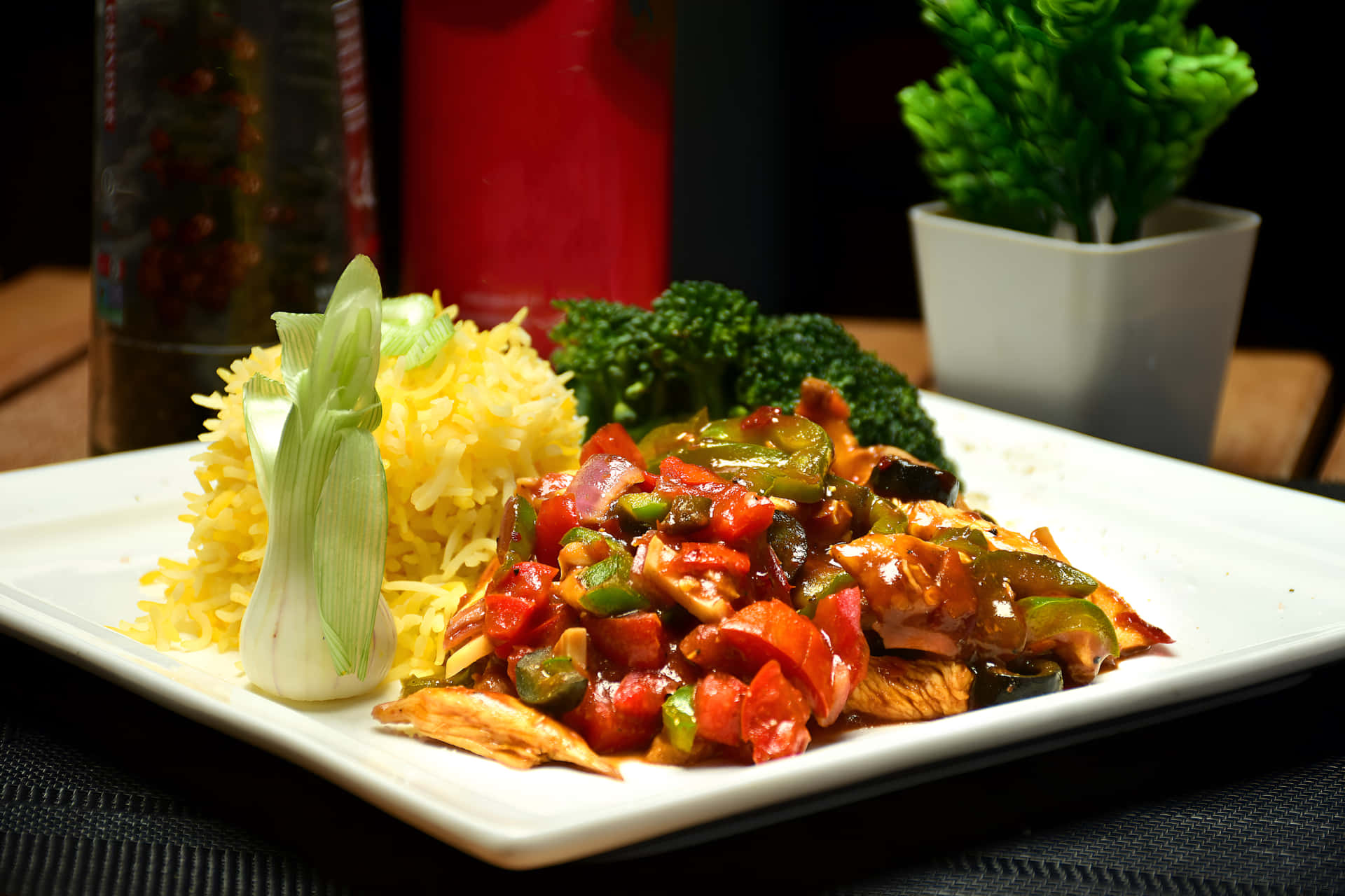 Chicken Chilli Dry with rice on a plate 壁紙 — 一盤色彩繽紛的炒雞肉、甜椒和花椰菜，配上黃米飯和青蔥，放在白色盤子上。