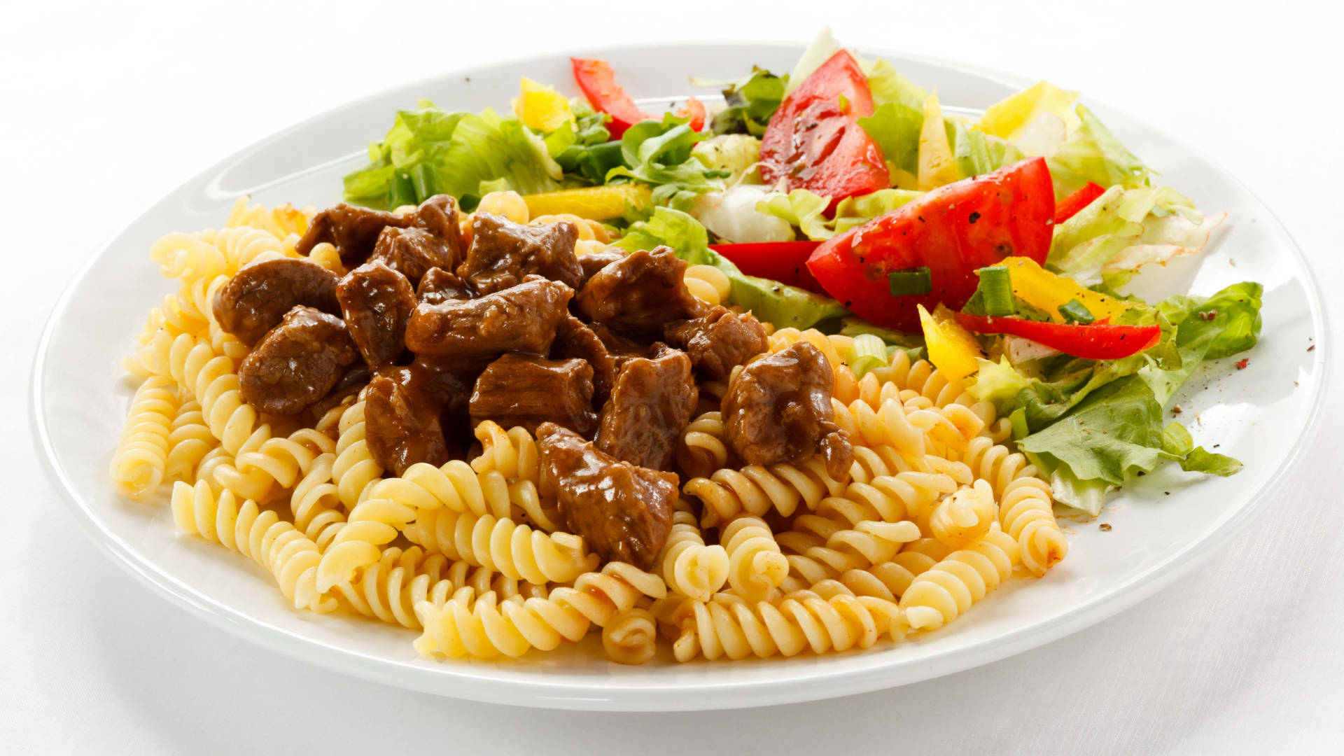 Pasta 桌布 壁紙 — 一盤螺旋義大利麵，上面放有美味的棕色肉塊和新鮮的配菜沙拉，配以紅番茄和綠色生菜。