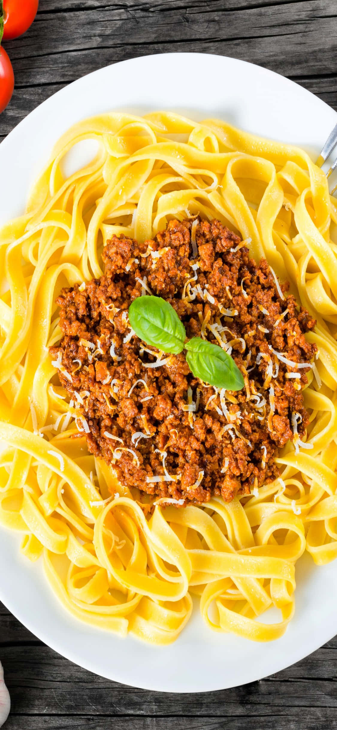 Food Photography 桌布 壁紙 — 一盤配有濃郁肉醬和新鮮羅勒的寬條麵放在質樸的木桌上。