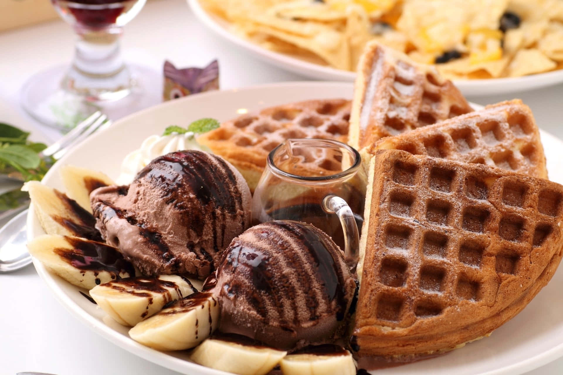 Waffle 桌布 壁紙 — 一盤金黃色鬆餅，上面放有巧克力冰淇淋、香蕉片和糖漿。