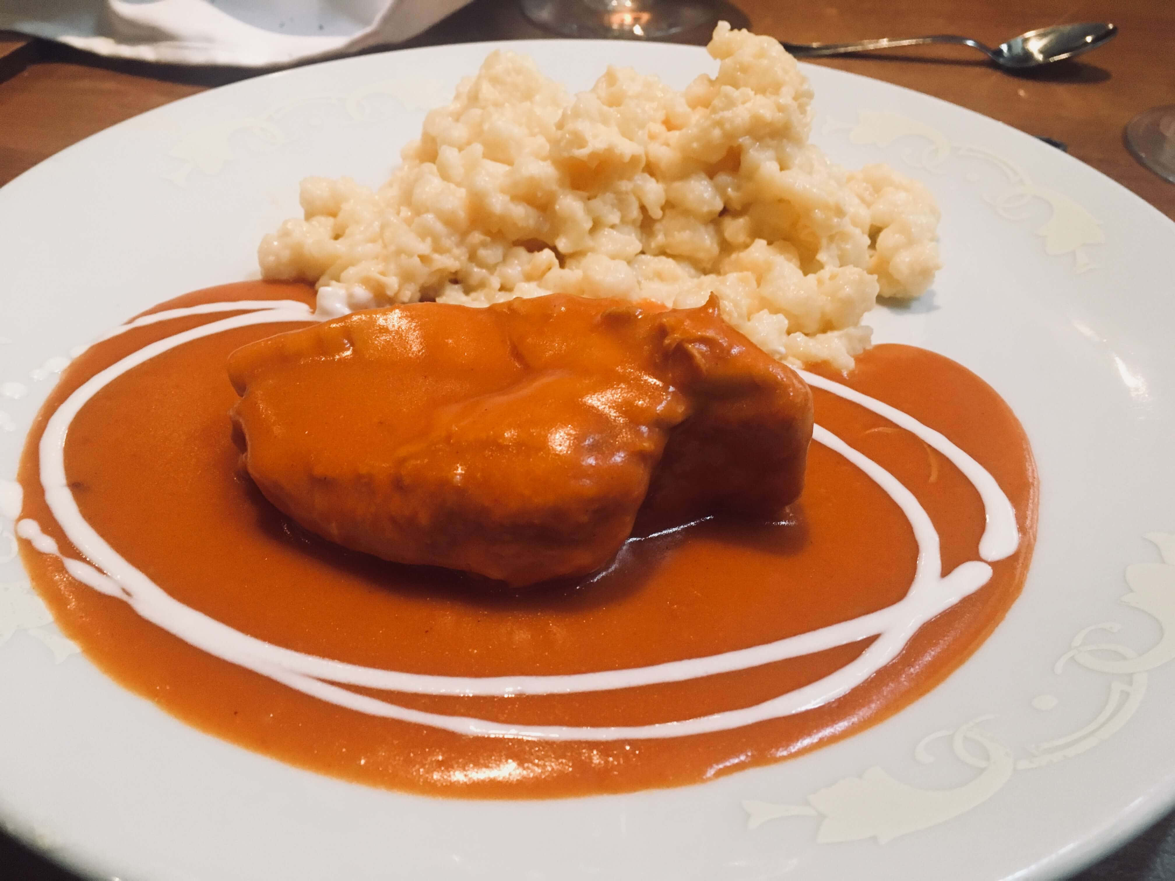 Chicken 桌布 壁紙 — 一盤雞肉搭配濃郁橙醬和奶油麵疙瘩，並以白色漩渦裝飾。