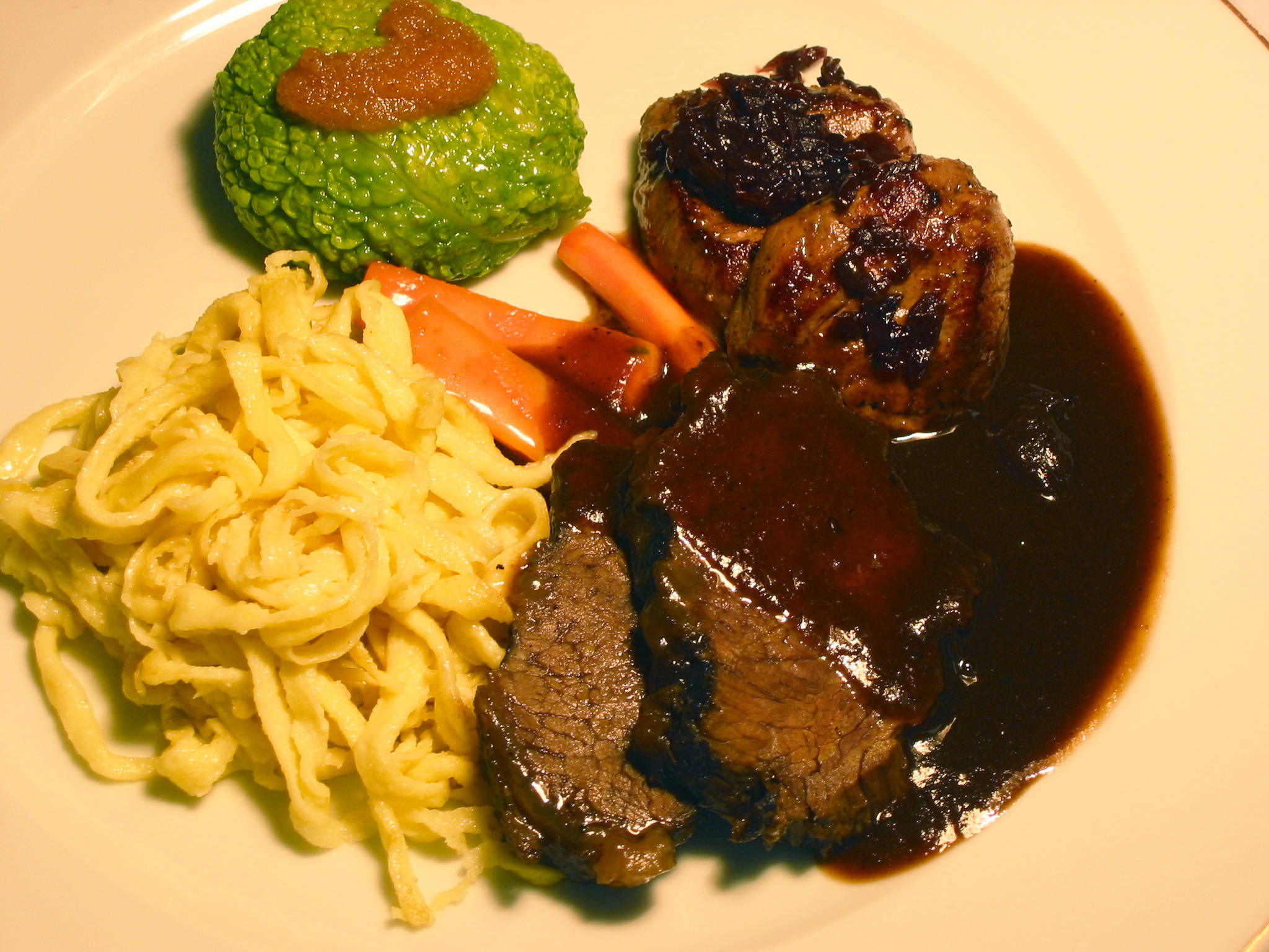 meat 桌布 壁紙 — 一盤香煎牛肉搭配濃郁肉汁，配上麵條、胡蘿蔔和綠色蔬菜，上面淋上醬汁。