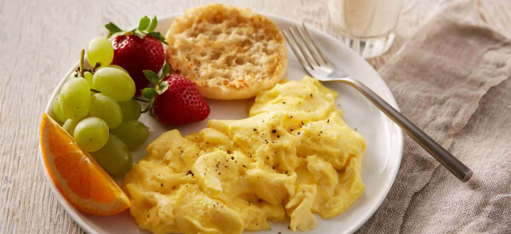 Scrambled Egg 桌布 壁紙 — 一盤鬆軟炒蛋撒上黑胡椒，搭配新鮮草莓、青葡萄和柳橙片，置於鄉村風木桌上。