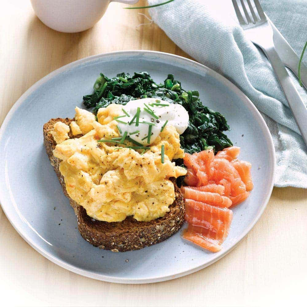 Scrambled Egg 桌布 壁紙 — 一盤鬆軟炒蛋放在吐司上，配上酸奶油和細香蔥，旁邊有炒菠菜和煙燻鮭魚。