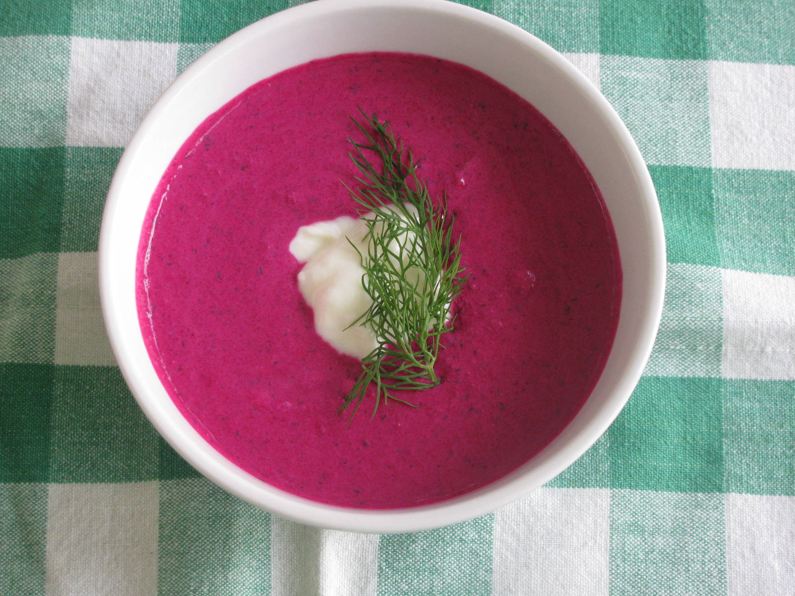 beetroot 桌布 壁紙 — 一碗充滿活力的紫紅色甜菜湯，盛在白色碗中，上面放有奶油和新鮮蒔蘿，置於綠色和白色格紋桌布上。