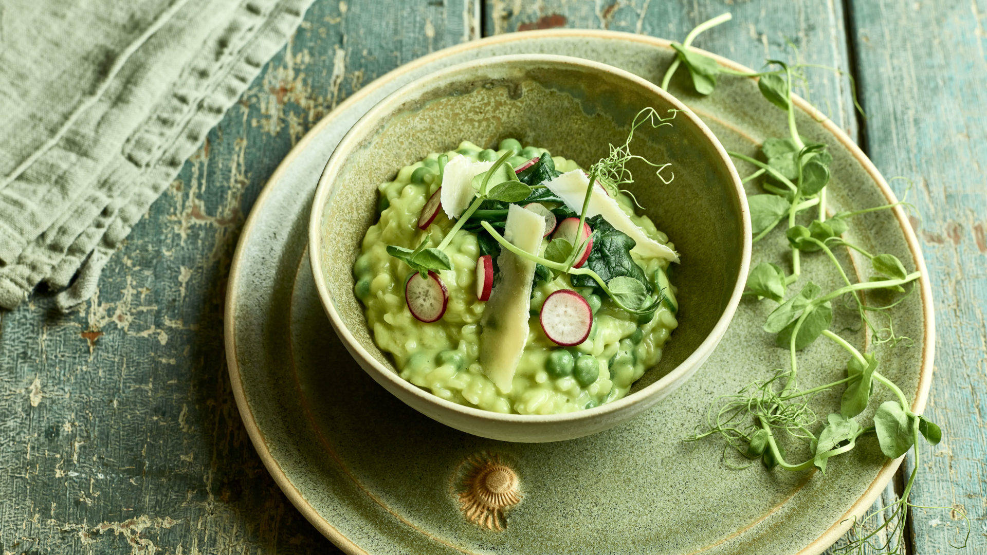 Healthy Food 桌布 壁紙 — 一碗充滿活力的青豆燴飯，上面放有蘿蔔片和微型蔬菜，放在一個質樸的綠色盤子上，背景是風化的木頭。