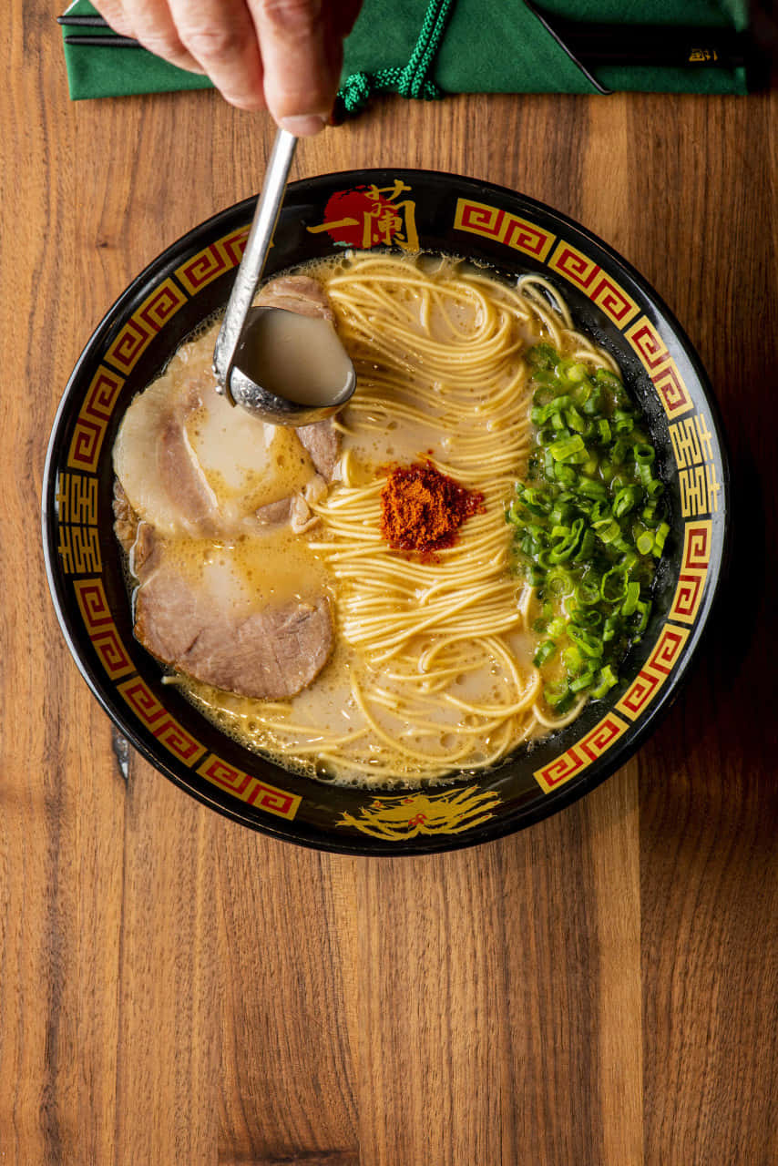 Noodles 桌布 壁紙 — 一碗冒煙的拉麵，有麵條、湯底、豬肉片、蔥花和辣椒油，正被湯匙舀起。