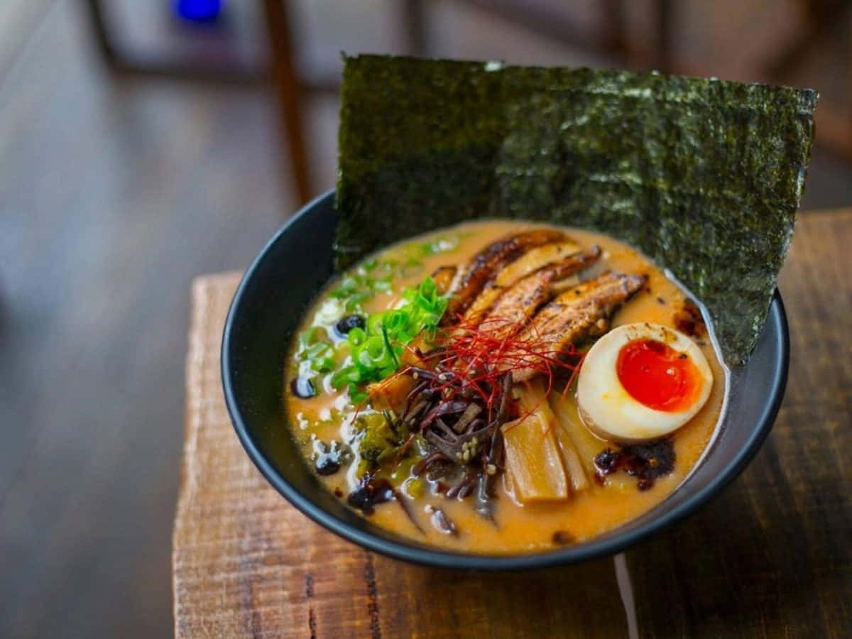 Noodles 桌布 壁紙 — 一碗冒煙的拉麵，配有溏心蛋、海苔和青蔥，放在木桌上。