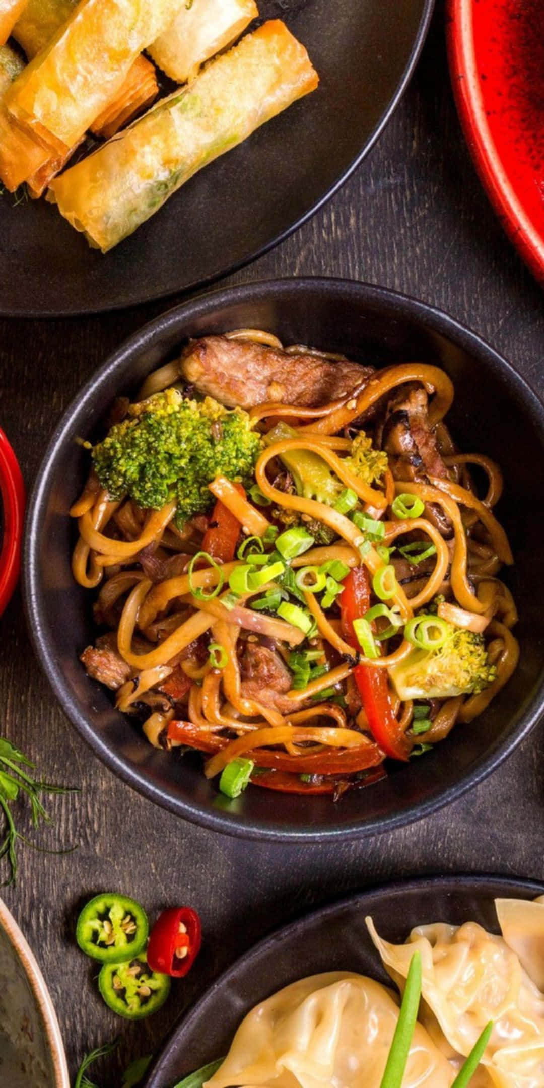 Food Photography 桌布 壁紙 — 一碗冒煙的炒烏龍麵，配有牛肉、花椰菜和青蔥，放在深色木桌上的特寫。