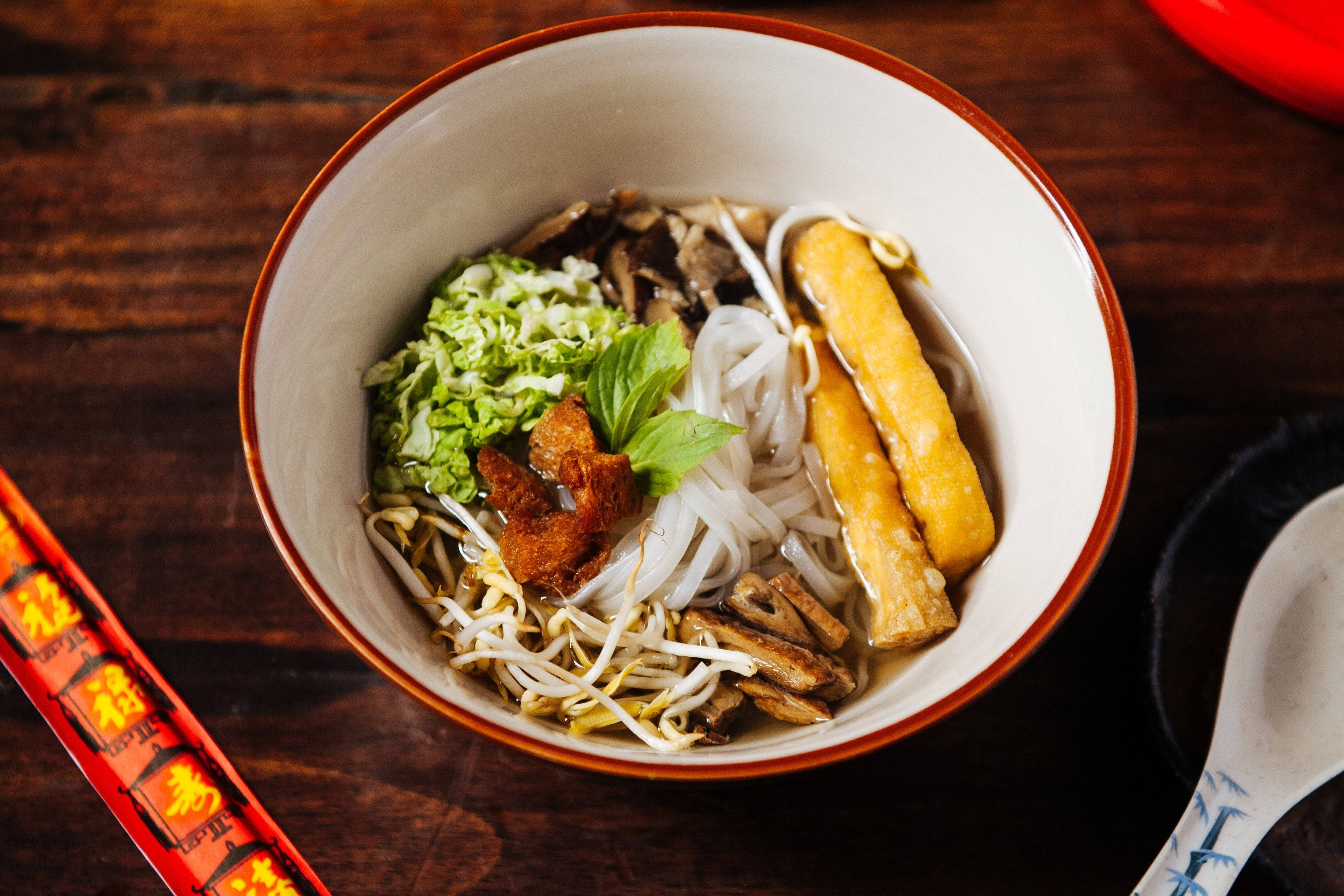 table 桌布 壁紙 — 一碗冒煙的越南河粉，配上米粉、豆芽、羅勒和炸豆腐，放在質樸的木桌上。