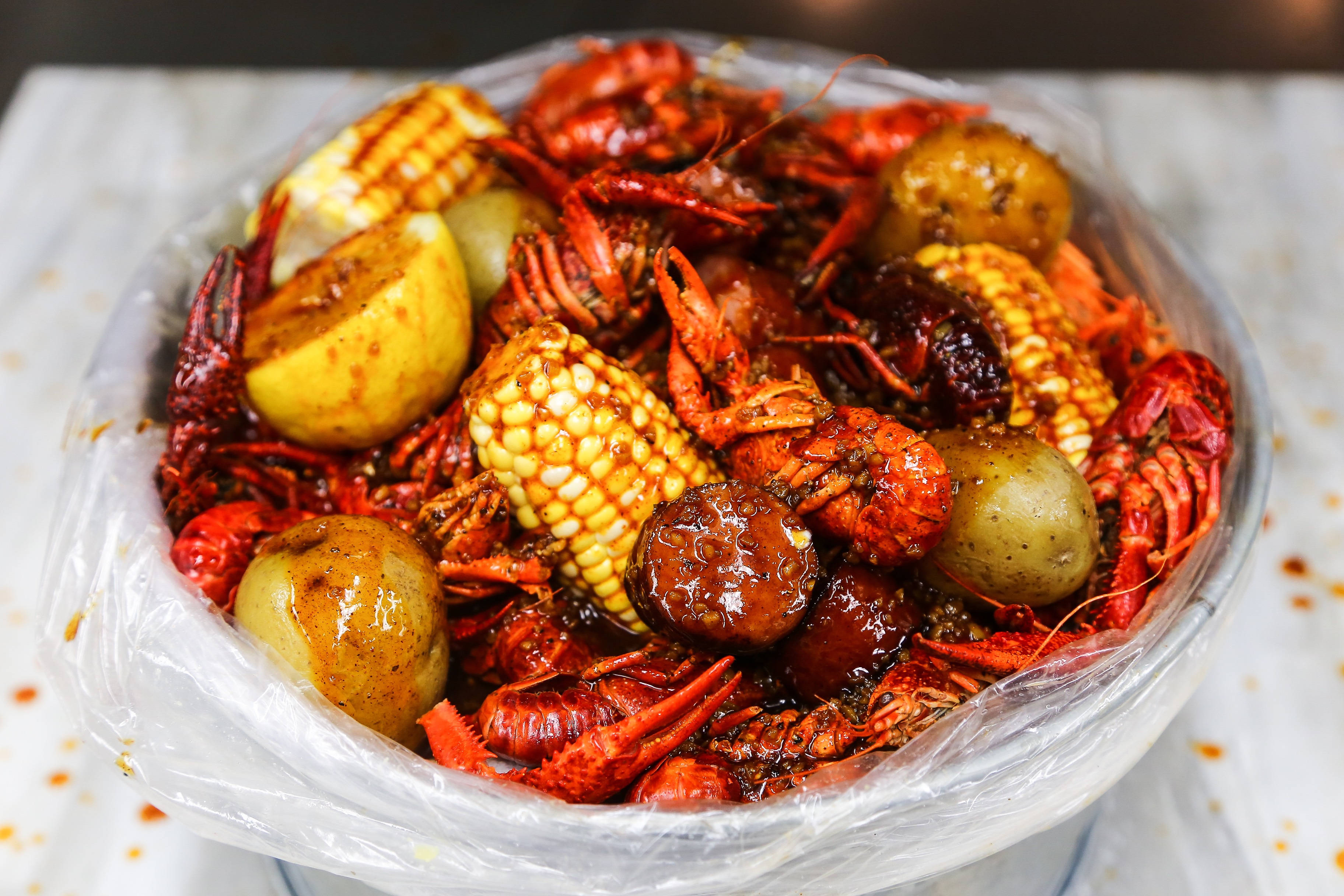 Seafood 桌布 壁紙 — 一碗冒煙的辣味小龍蝦，搭配玉米和馬鈴薯，裹上光亮的紅醬。