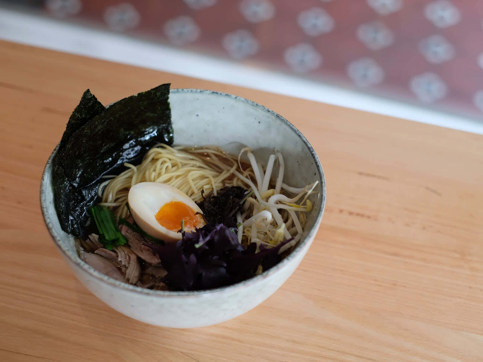 Noodles 桌布 壁紙 — 一碗冒著熱氣的拉麵，配有溏心蛋、豆芽和紫菜，放在木桌上。