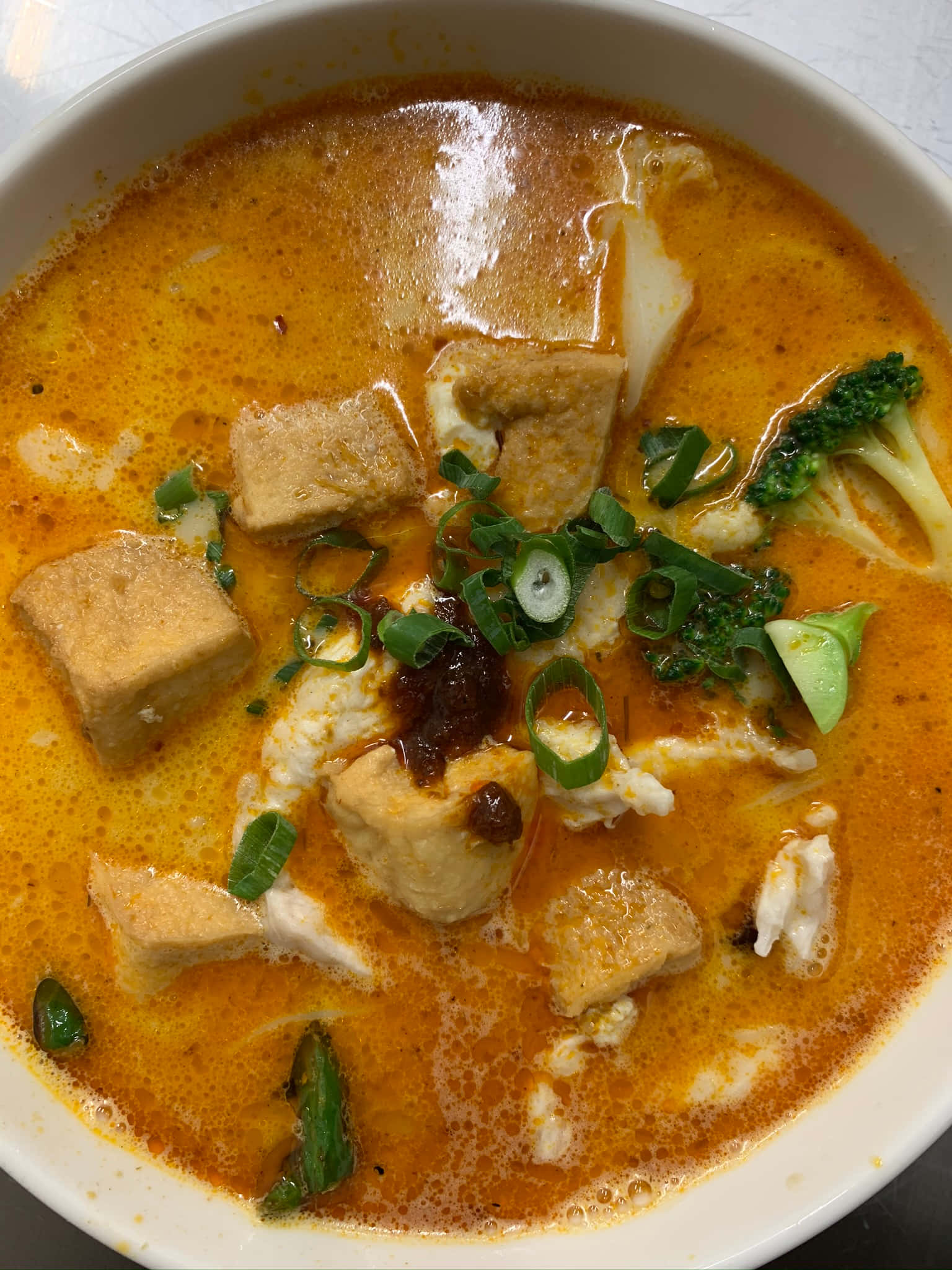Soup 桌布 壁紙 — 一碗冒著熱氣的濃郁橙色咖哩湯，搭配豆腐魚和青花菜，並以青蔥點綴。
