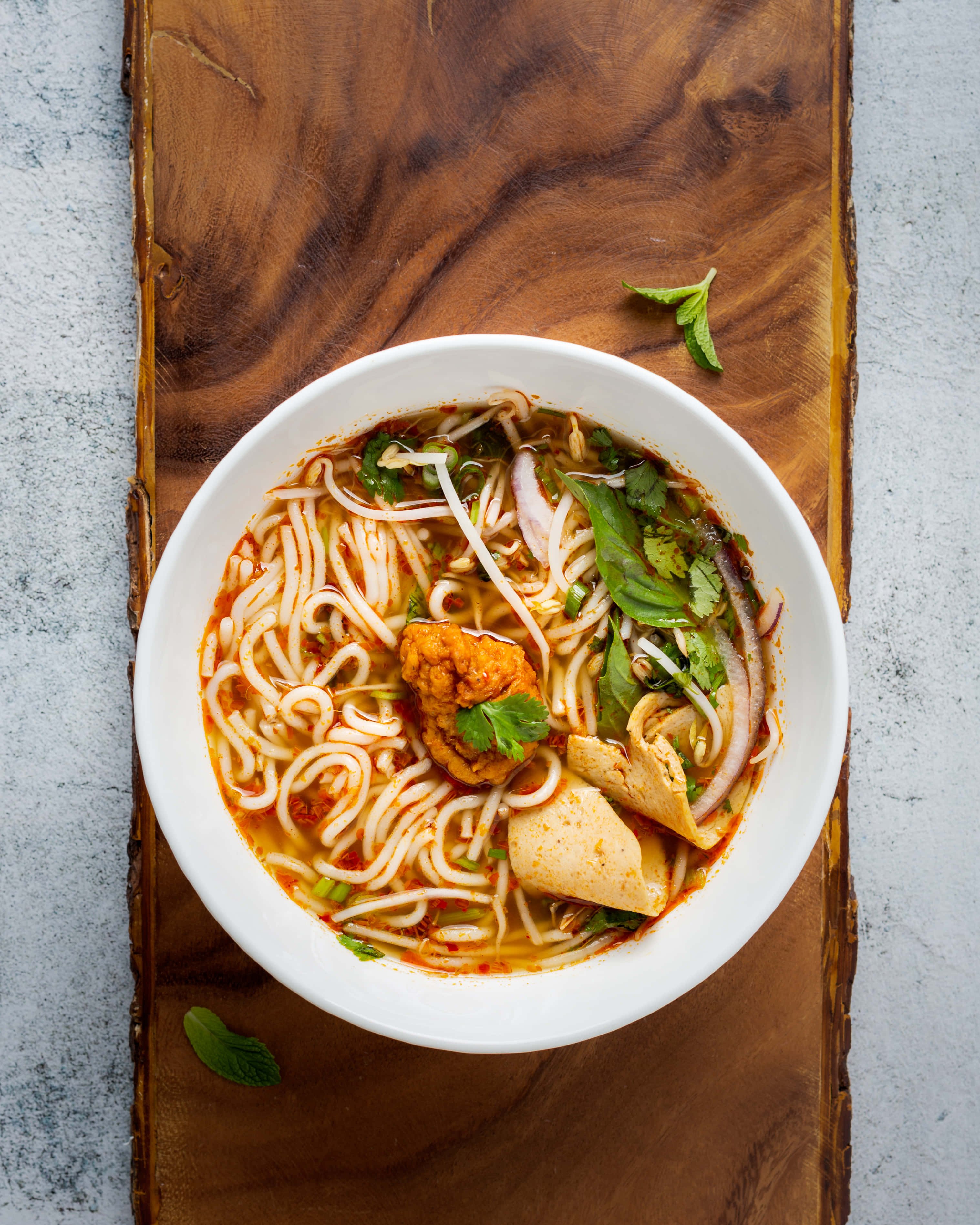 Noodles 桌布 壁紙 — 一碗冒著熱氣的色彩繽紛湯麵，配上香草和豆腐，放在質樸的木板上。