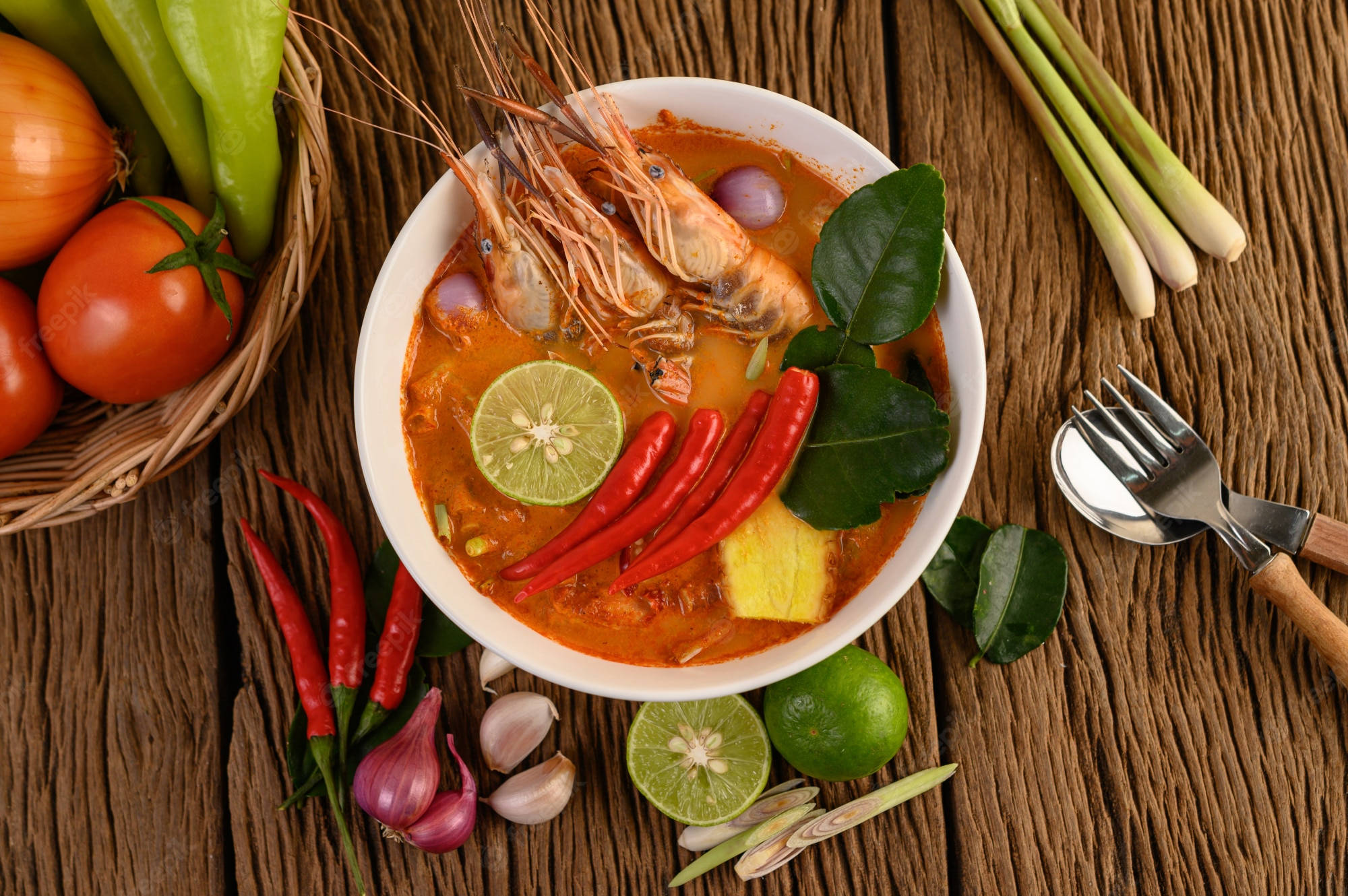 Food Photography 桌布 壁紙 — 一碗冒著熱氣的辛辣泰式冬陰功湯，配有蝦、青檸和辣椒，放在一個鄉村風格的木桌上，周圍是新鮮食材。