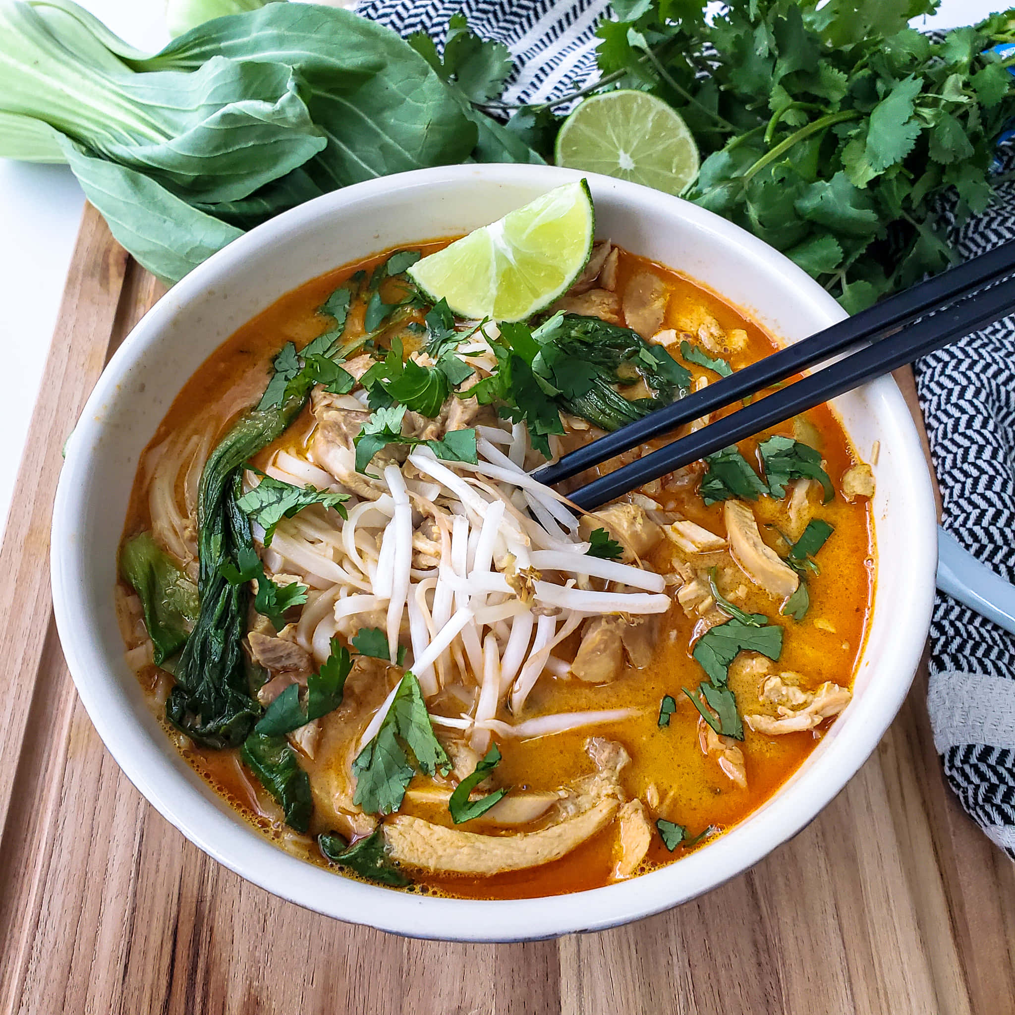 Soup 桌布 壁紙 — 一碗冒著熱氣的鮮橙色咖哩湯麵，上面放著新鮮的香菜、萊姆和豆芽，放在木板上。