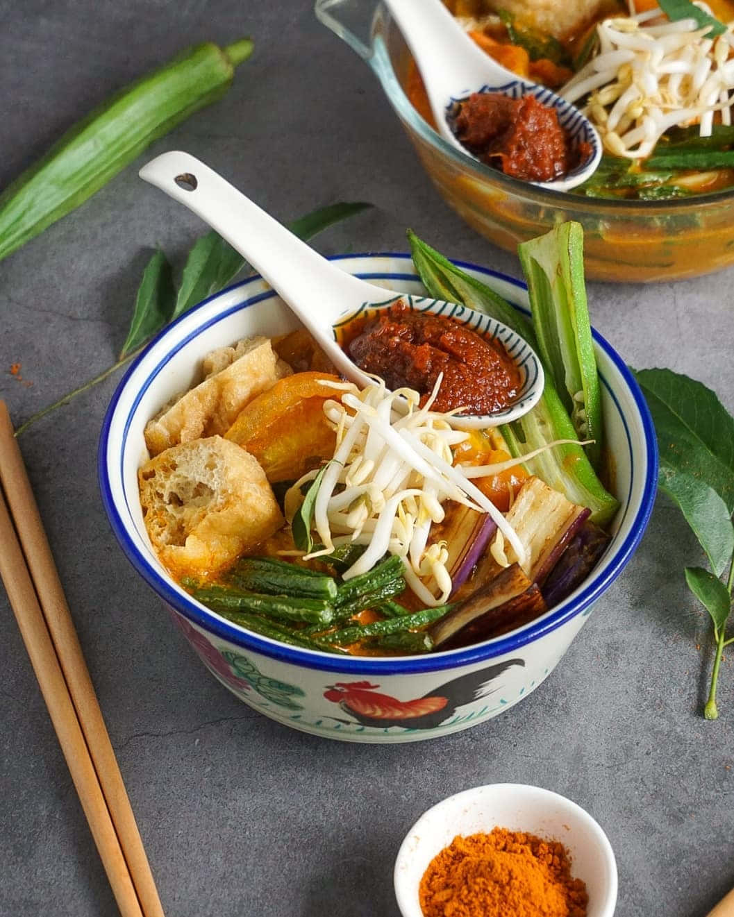 Dish 桌布 壁紙 — 一碗冒著蒸氣的東南亞風味麵湯，上面放有豆芽、秋葵、豆腐和辣椒醬。