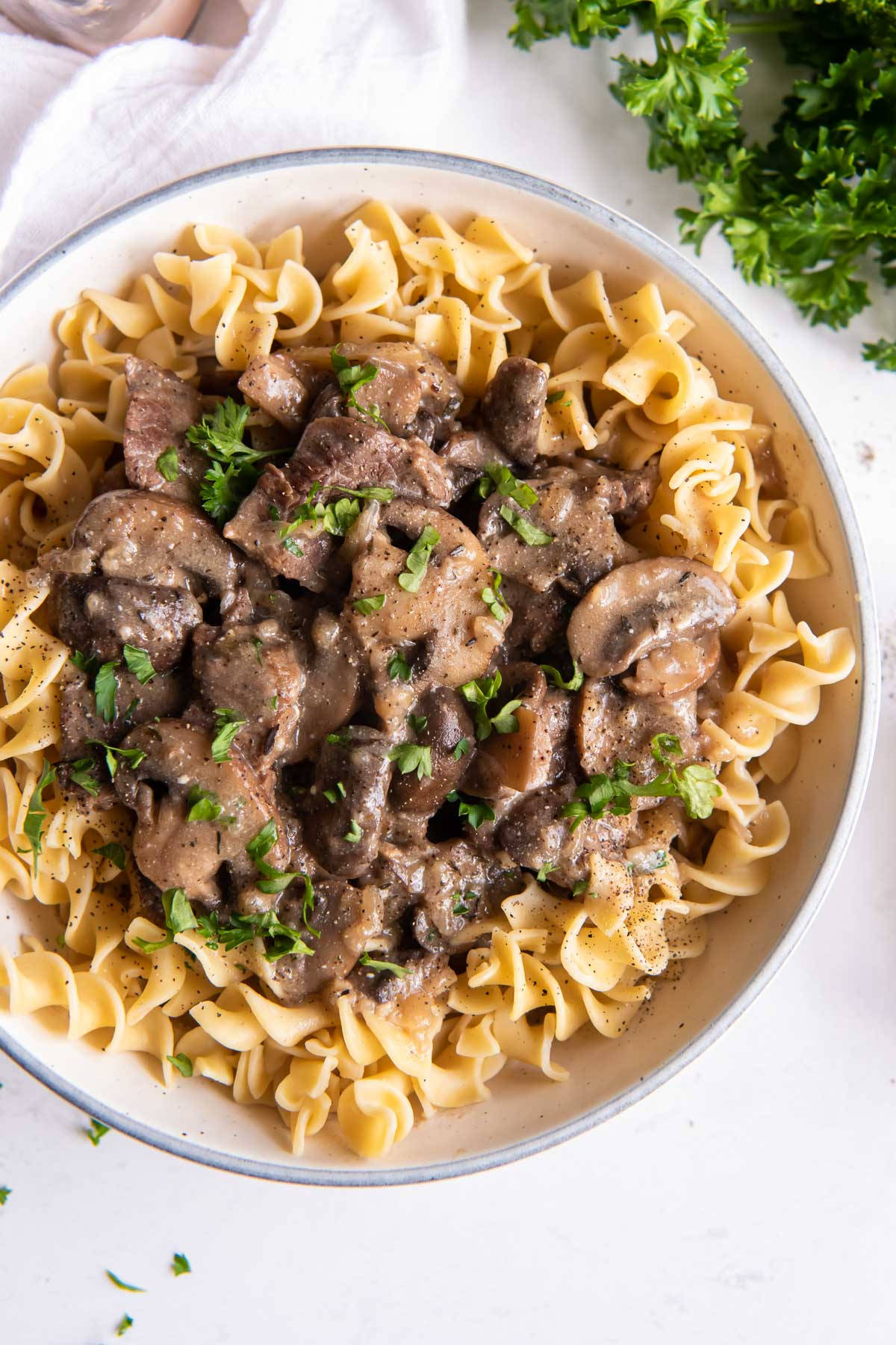 food iPhone 桌布 壁紙 — 一碗奶油牛肉斯特羅加諾夫，搭配蘑菇和新鮮歐芹，放在雞蛋麵上。