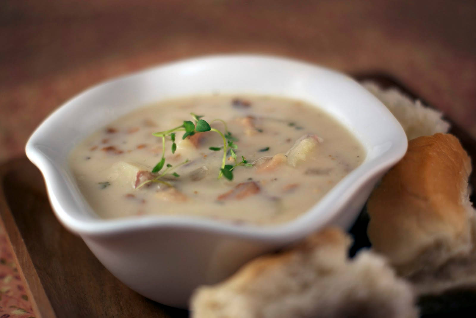 Soup 桌布 壁紙 — 一碗奶油白色湯品，飾以新鮮綠色香草，放在白色碗中，旁邊是木托盤上的脆皮麵包。