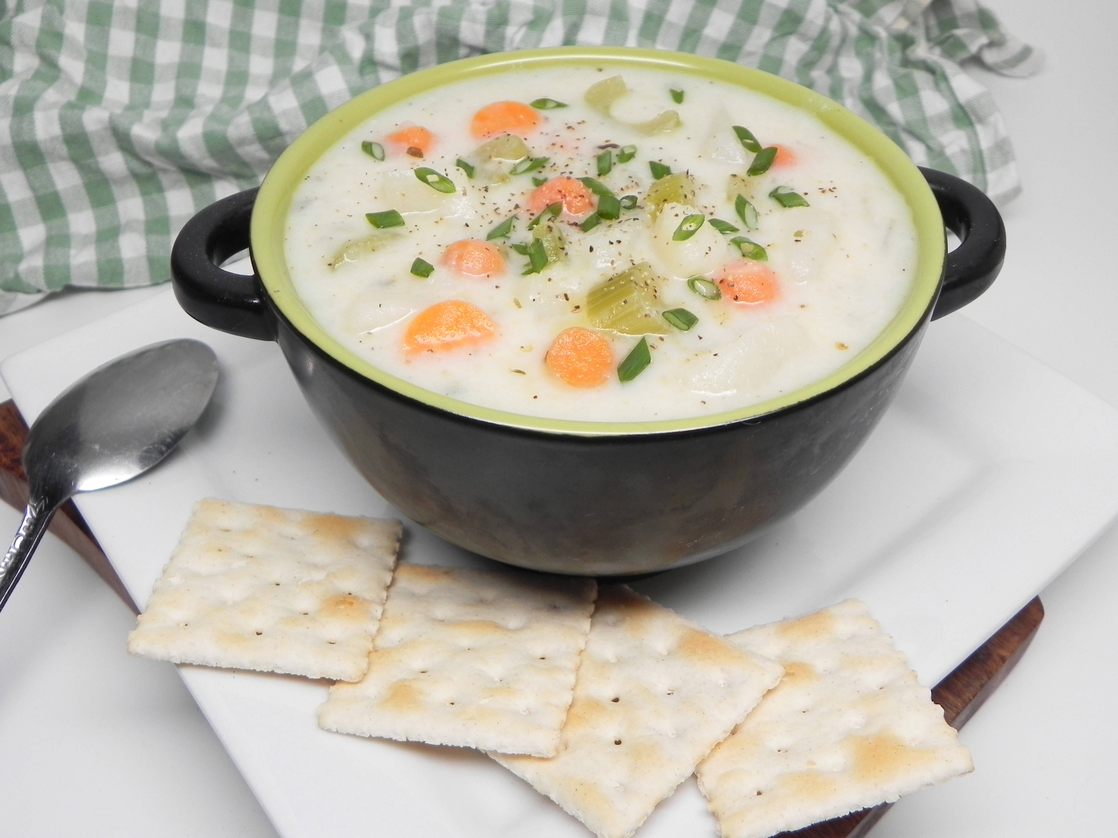 Chowder 桌布 壁紙 — 一碗奶油蔬菜湯，飾以青蔥和紅蘿蔔，旁邊放著白色盤子上的鹹餅乾。