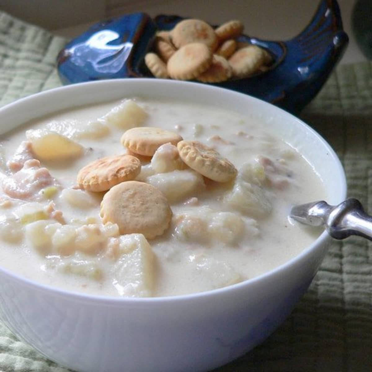 Soup 桌布 壁紙 — 一碗奶油蛤蜊濃湯，上面放著圓形餅乾，旁邊放著一個藍色盤子，裡面有更多餅乾，放在綠色布上。