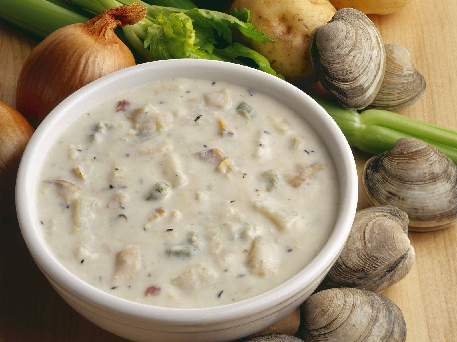 Soup 桌布 壁紙 — 一碗奶油蛤蜊濃湯，周圍放著新鮮蛤蜊、洋蔥、芹菜和馬鈴薯，置於木質表面上。