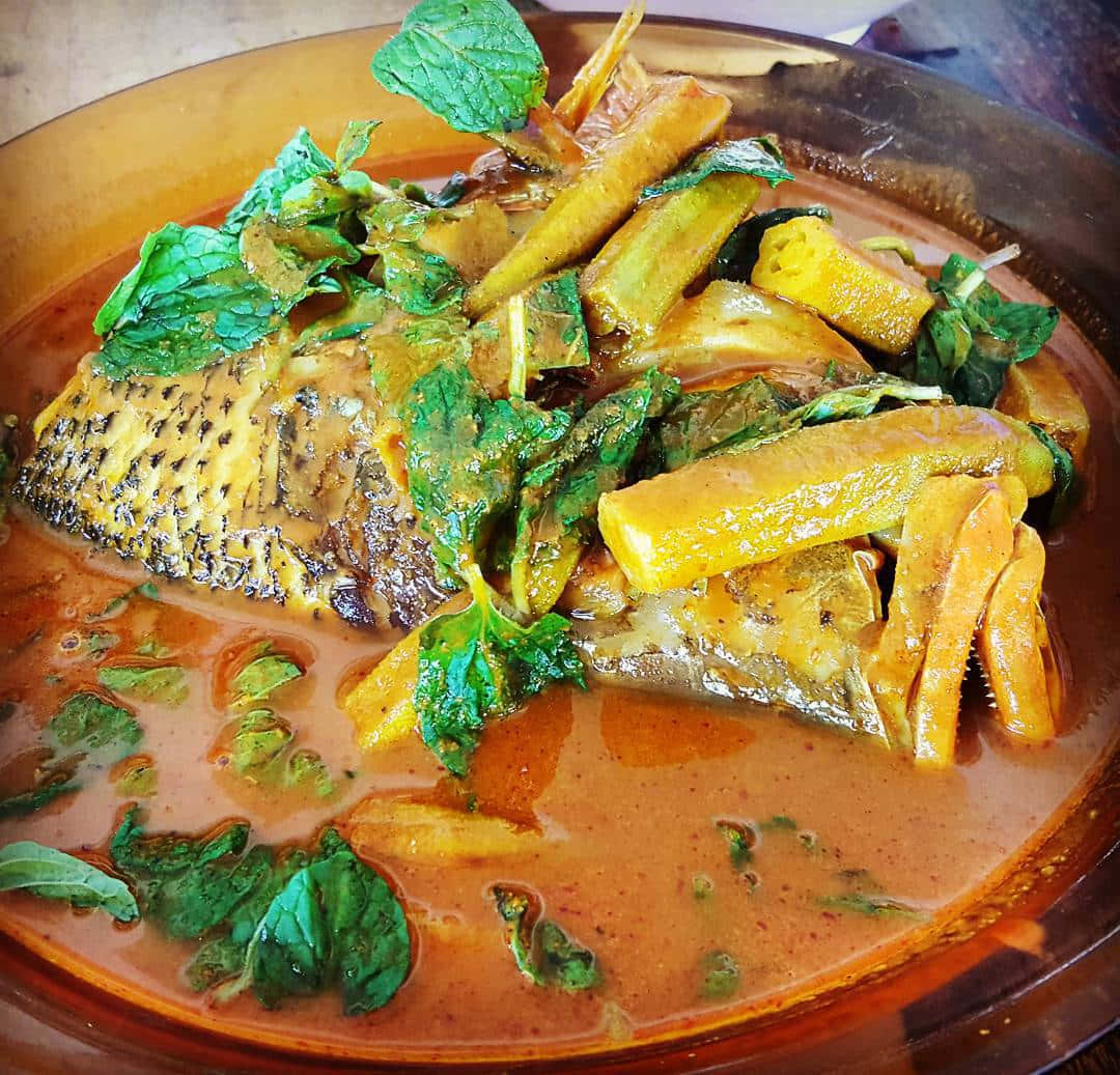 Food Photography 桌布 壁紙 — 一碗熱氣騰騰的香辣魚咖哩，內有嫩滑魚塊、黃色蔬菜和新鮮薄荷葉，配上光澤醬汁。