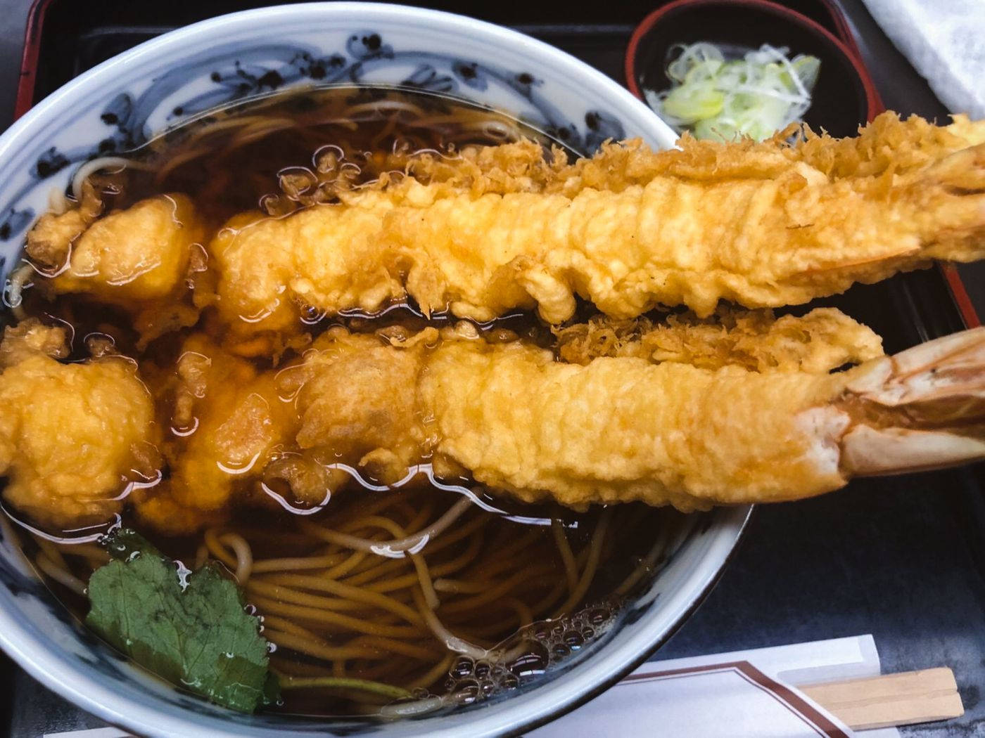 Noodles 桌布 壁紙 — 一碗熱騰騰的天婦羅烏冬近照，配有金黃酥脆的炸蝦和蔬菜，浸泡在鮮美的湯汁中。