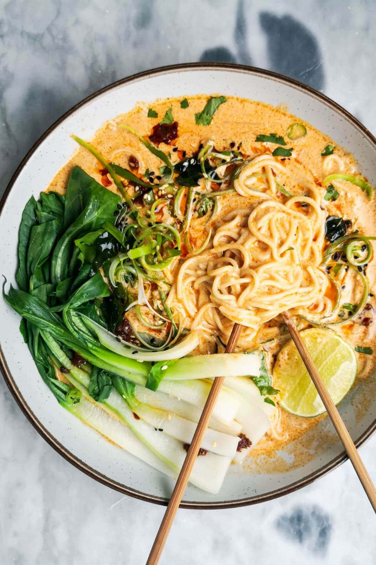 Noodles 桌布 壁紙 — 一碗熱騰騰的奶油咖哩湯麵，配上新鮮蔬菜、萊姆和辣椒油，筷子準備好享用。