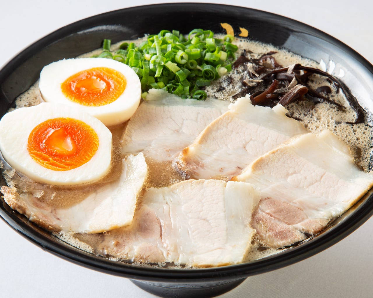 Ramen 桌布 壁紙 — 一碗熱騰騰的拉麵，配上溏心蛋、青蔥和豬肉片，浸在濃郁湯頭中。