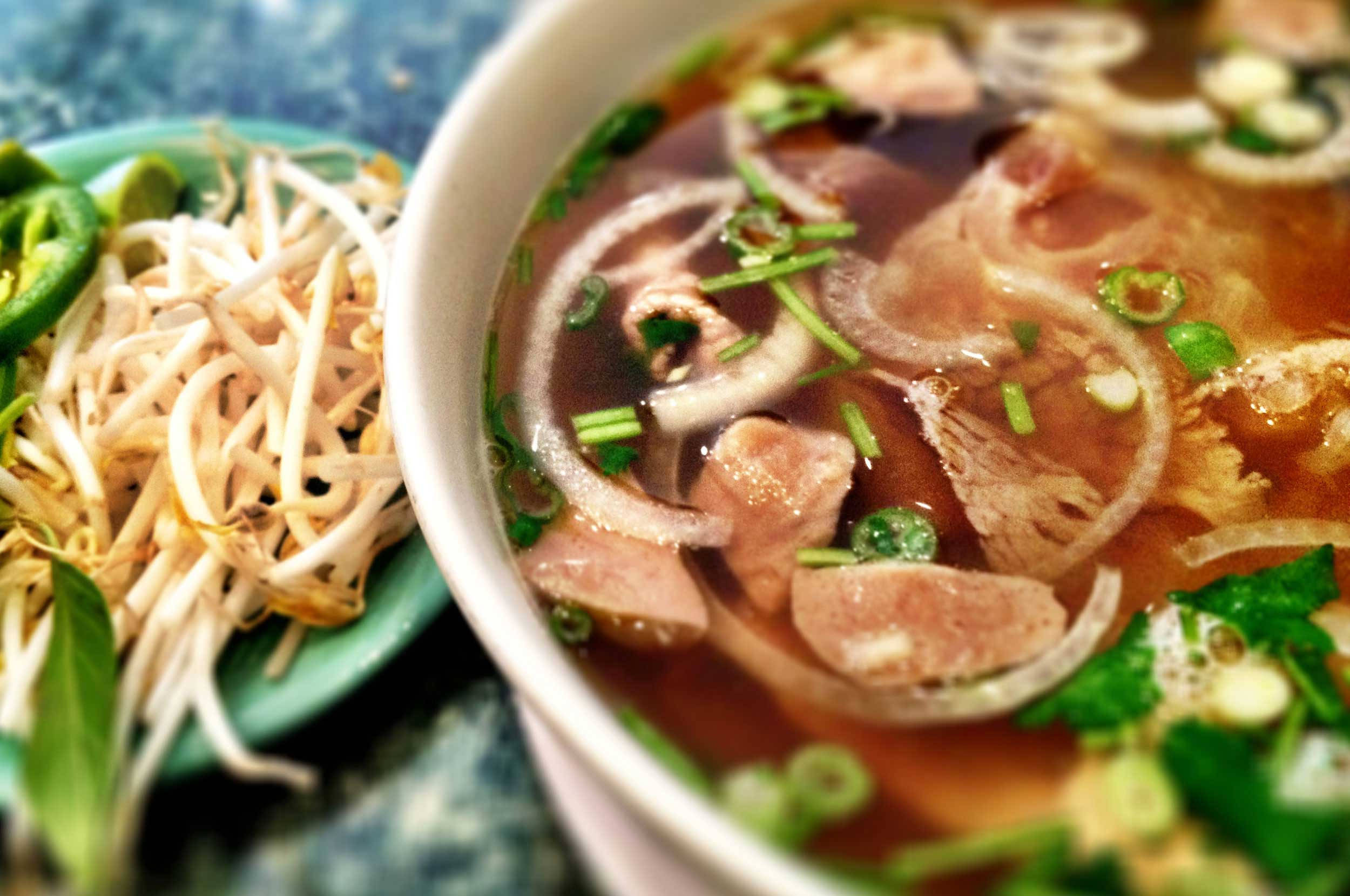 Noodles 桌布 壁紙 — 一碗熱騰騰的濃湯，裡面有切片肉、洋蔥和新鮮香草，旁邊放著一碟豆芽和墨西哥辣椒。