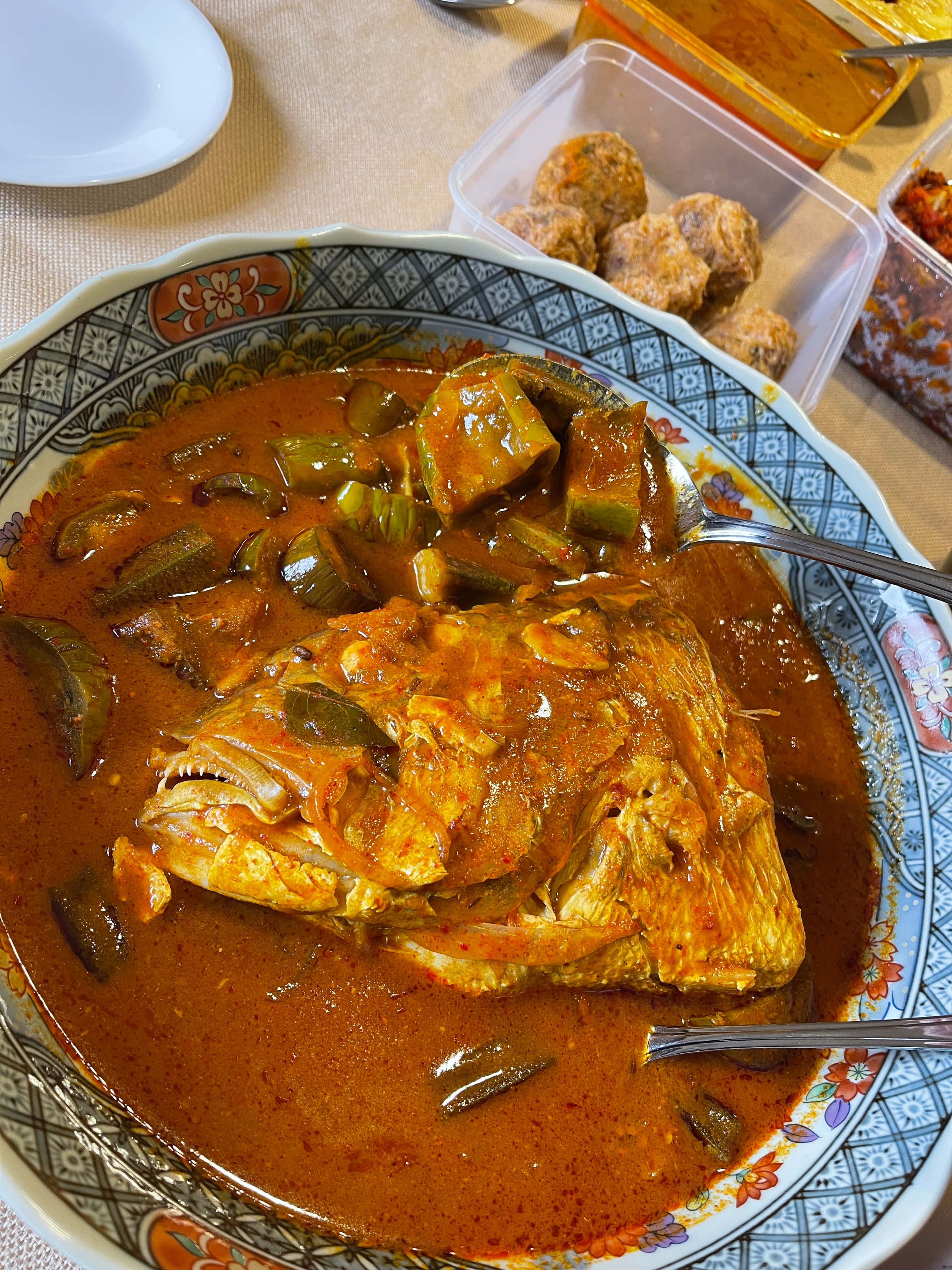 Food Photography 桌布 壁紙 — 一碗熱騰騰的濃郁紅咖哩魚，配有整條魚頭和青辣椒，盛載於有圖案的陶瓷碗中。