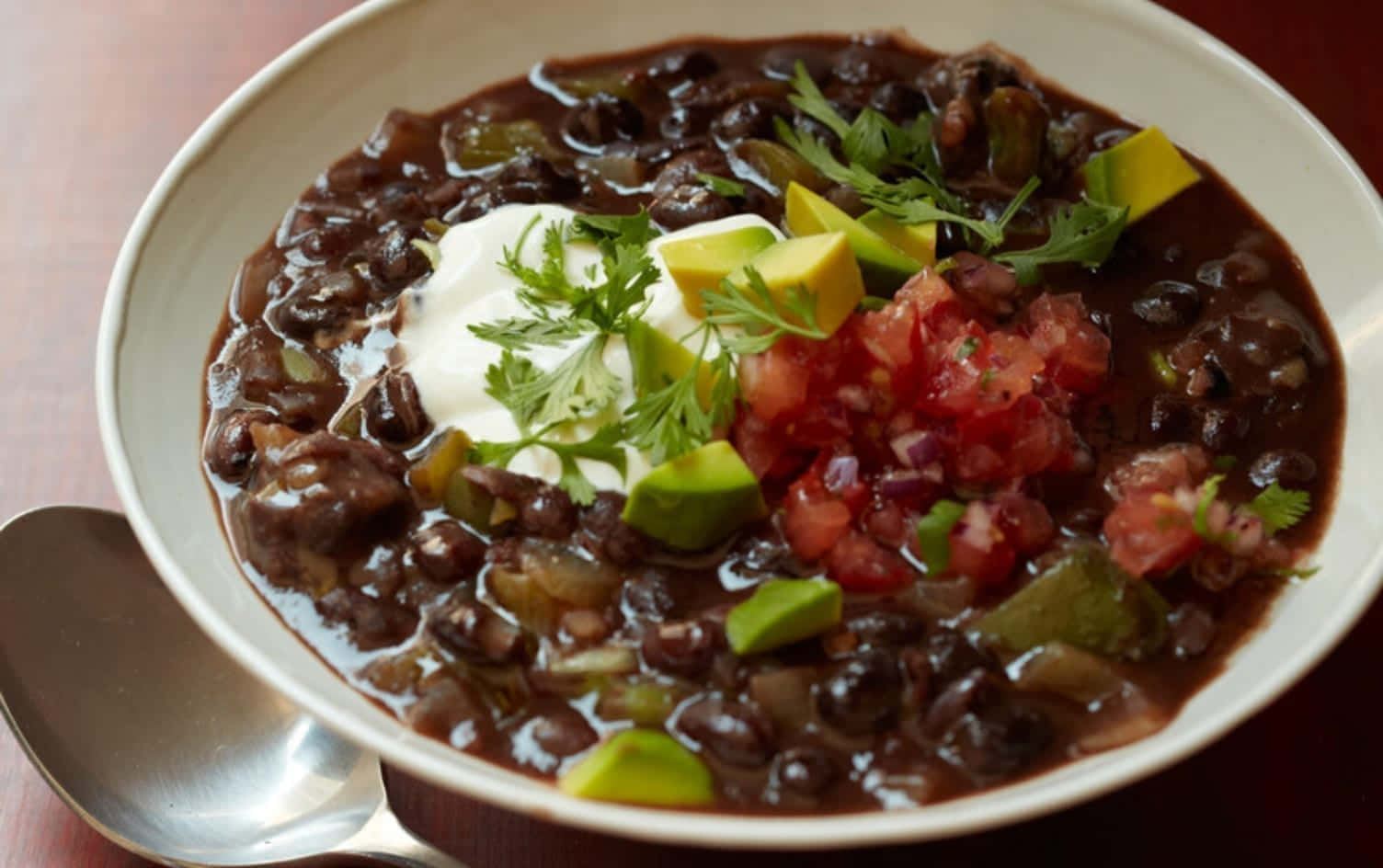 Black Bean Soup 桌布 壁紙 — 一碗熱騰騰的濃郁黑豆辣椒，上面放有酸奶油、酪梨和新鮮莎莎醬。