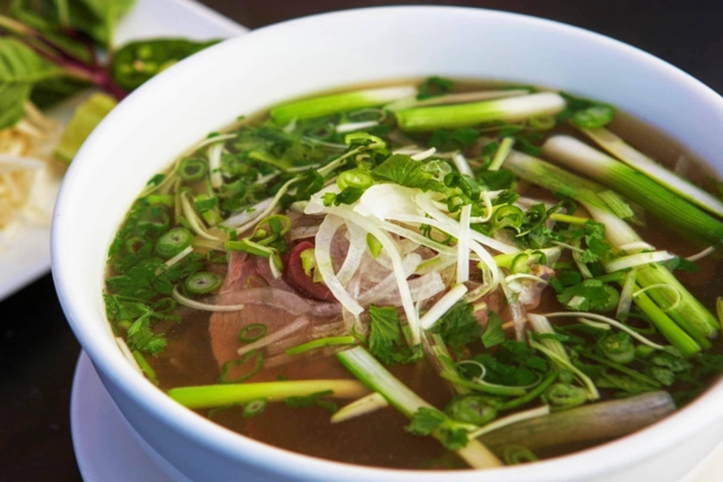 meat 桌布 壁紙 — 一碗熱騰騰的越南河粉，配上嫩牛肉片、新鮮香草和青蔥，浸在濃郁的湯頭中。