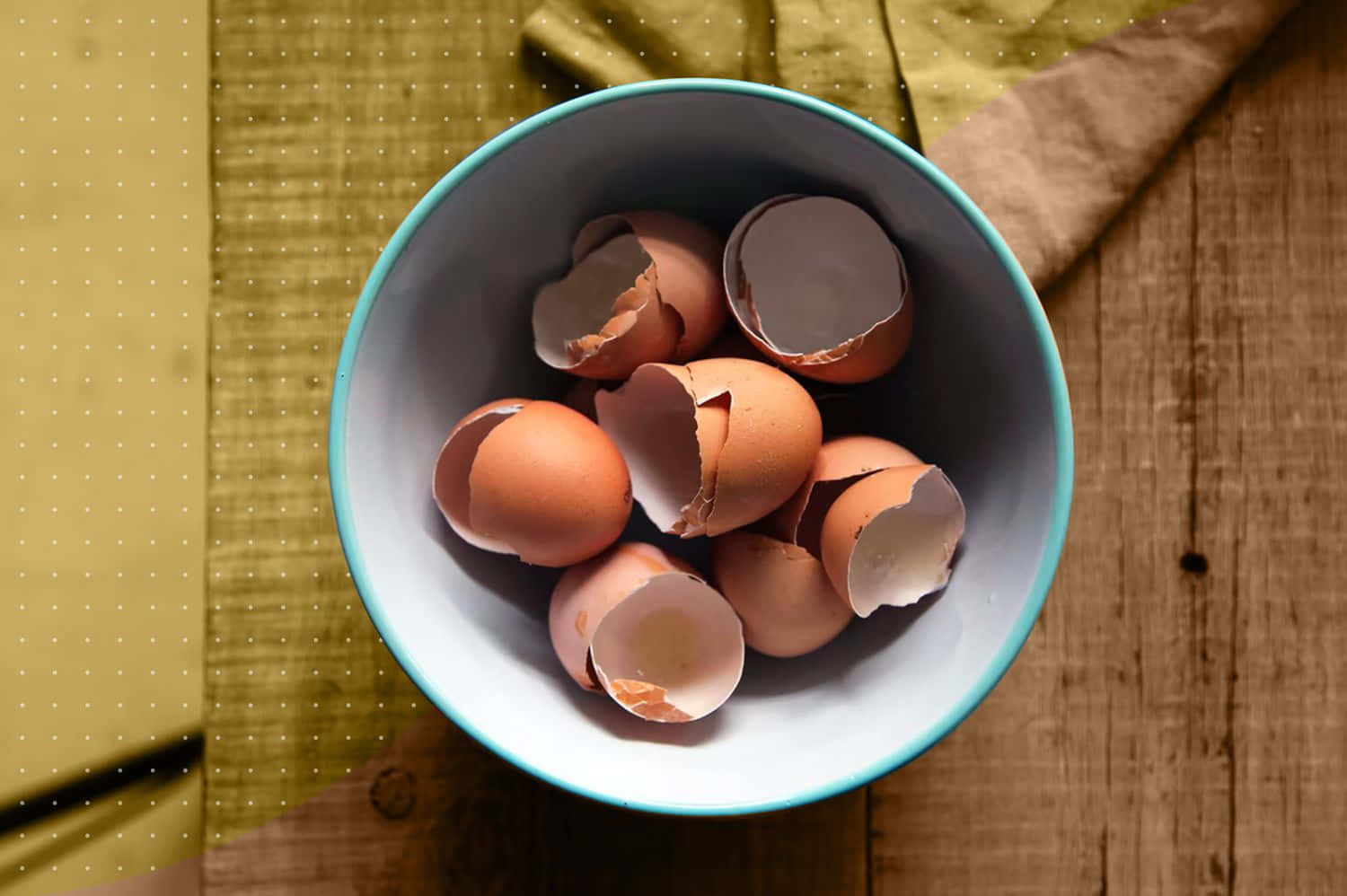 Egg 桌布 壁紙 — 一碗碎掉的棕色蛋殼放在木桌上，旁邊有一塊黃色布。