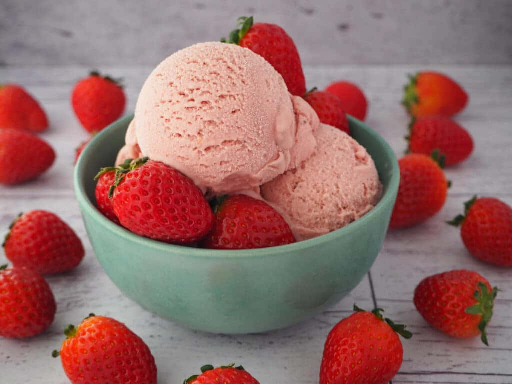 Strawberries 桌布 壁紙 — 一碗粉紅色草莓冰淇淋放在白色木面上，周圍是新鮮的紅色草莓。