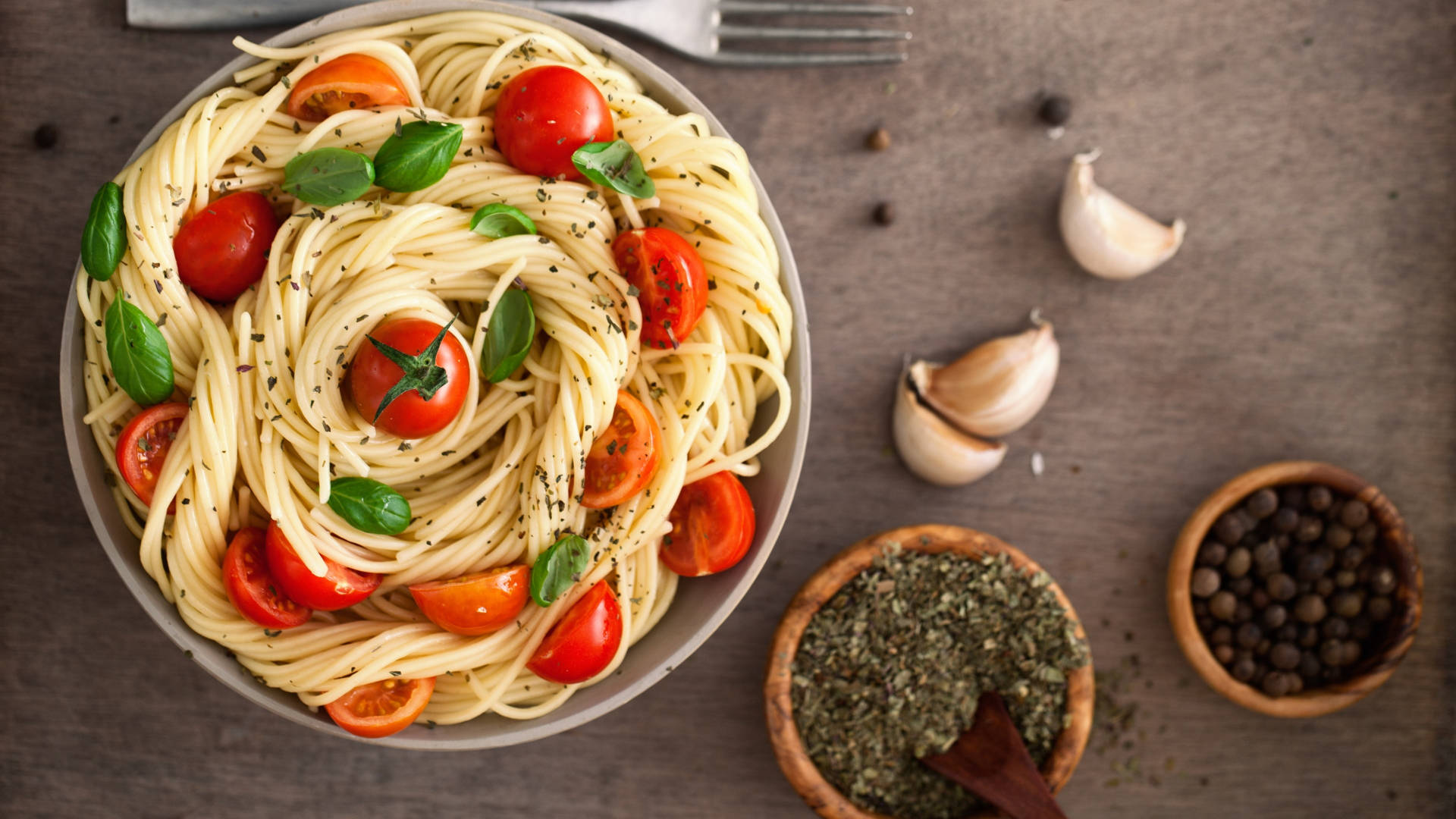 Pasta 桌布 壁紙 — 一碗義大利麵的俯視圖，上面放有櫻桃番茄、羅勒和黑胡椒，放在質樸的木質表面上。