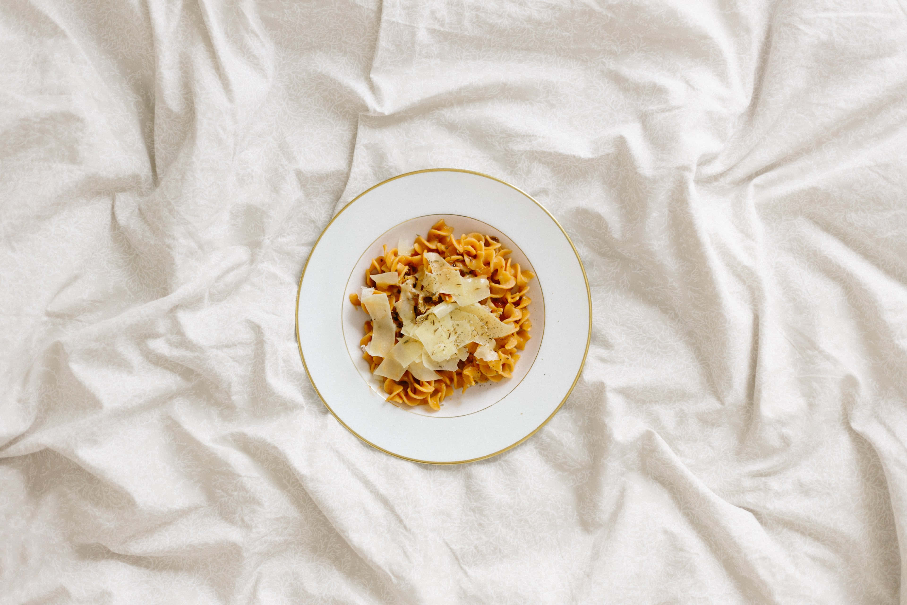 4K Pasta 桌布 壁紙 — 一碗義大利麵配上刨起司，放在皺巴巴的白色亞麻布上，以極簡風格俯拍。