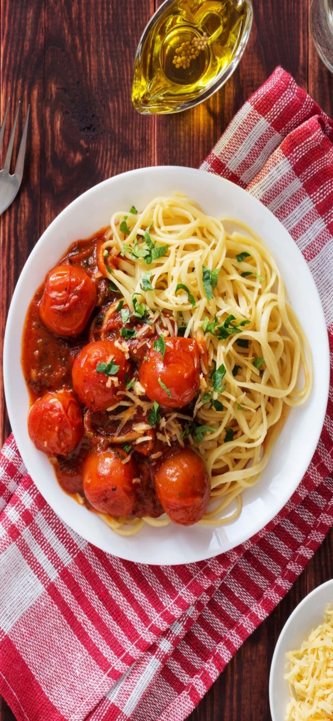 Spaghetti 桌布 壁紙 — 一碗義大利麵配番茄醬和烤櫻桃番茄，撒上歐芹，放在紅白格紋布上。