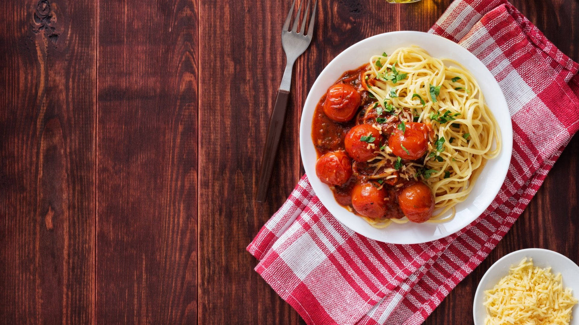 Pasta 桌布 壁紙 — 一碗肉丸番茄醬義大利麵放在深色木桌上的一塊紅色格子餐巾上。