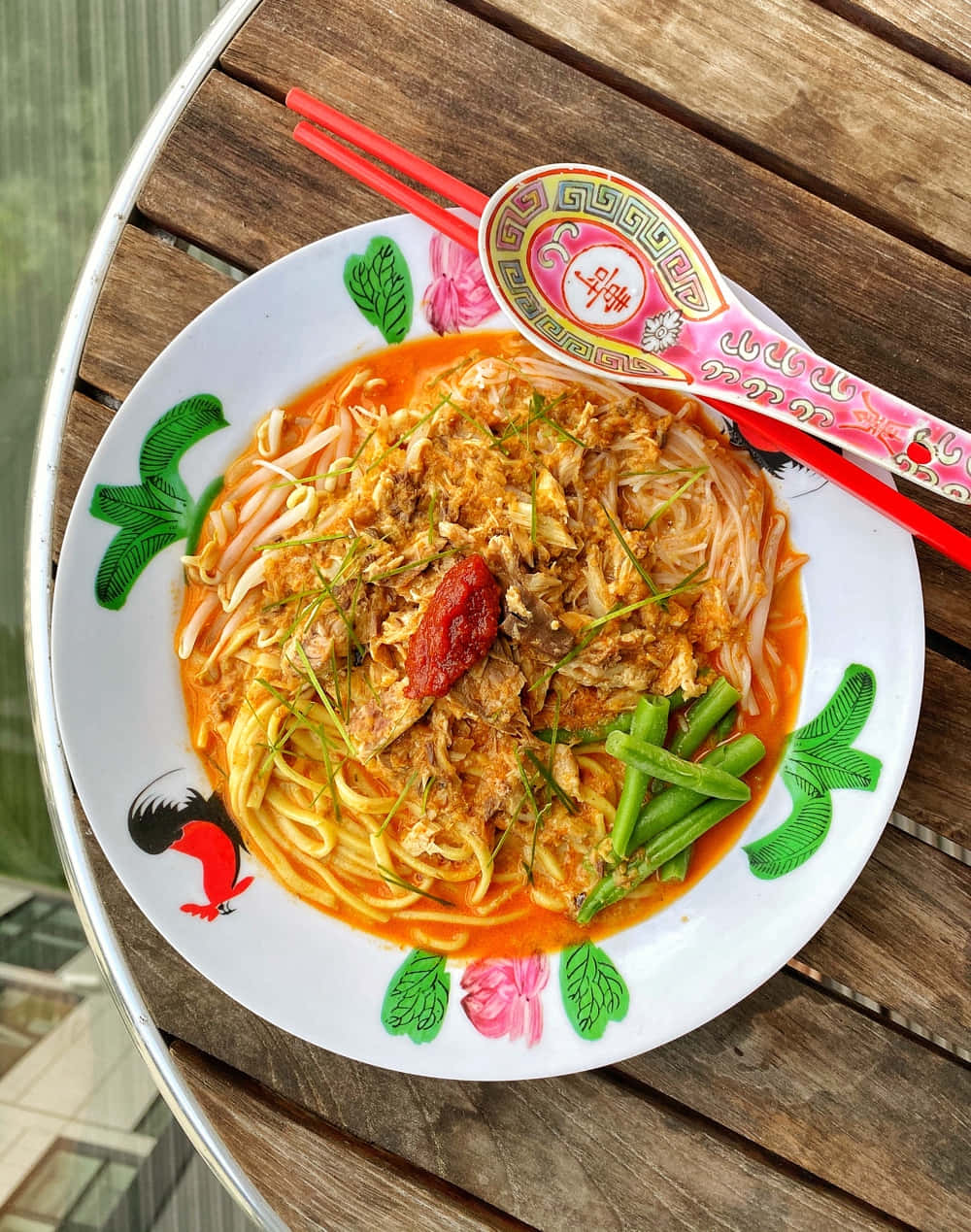 Noodles 桌布 壁紙 — 一碗色彩繽紛的湯麵，配上肉絲、辣椒、豆芽和四季豆，放在木桌上，旁邊有紅色筷子及裝飾湯匙。