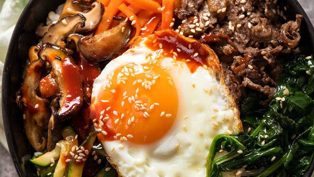 烹飪 桌布 壁紙 — 一碗色彩繽紛的韓國石鍋拌飯，上面放著太陽蛋、芝麻和色彩繽紛的炒蔬菜。