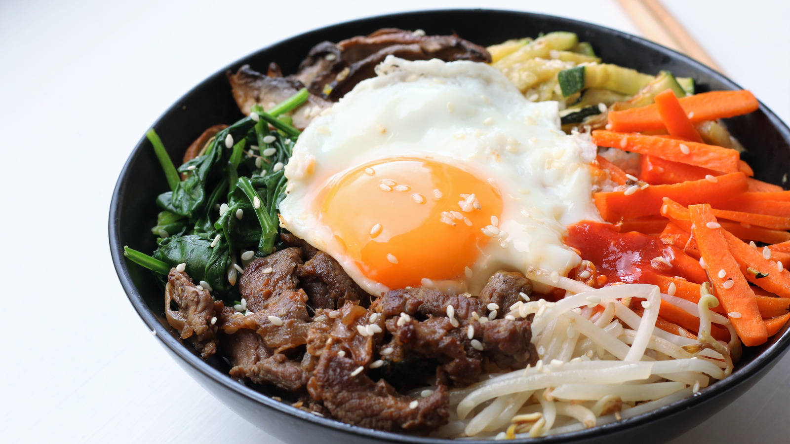 烹飪 桌布 壁紙 — 一碗色彩繽紛的韓國石鍋拌飯，上面放著太陽蛋、芝麻和五顏六色的蔬菜。