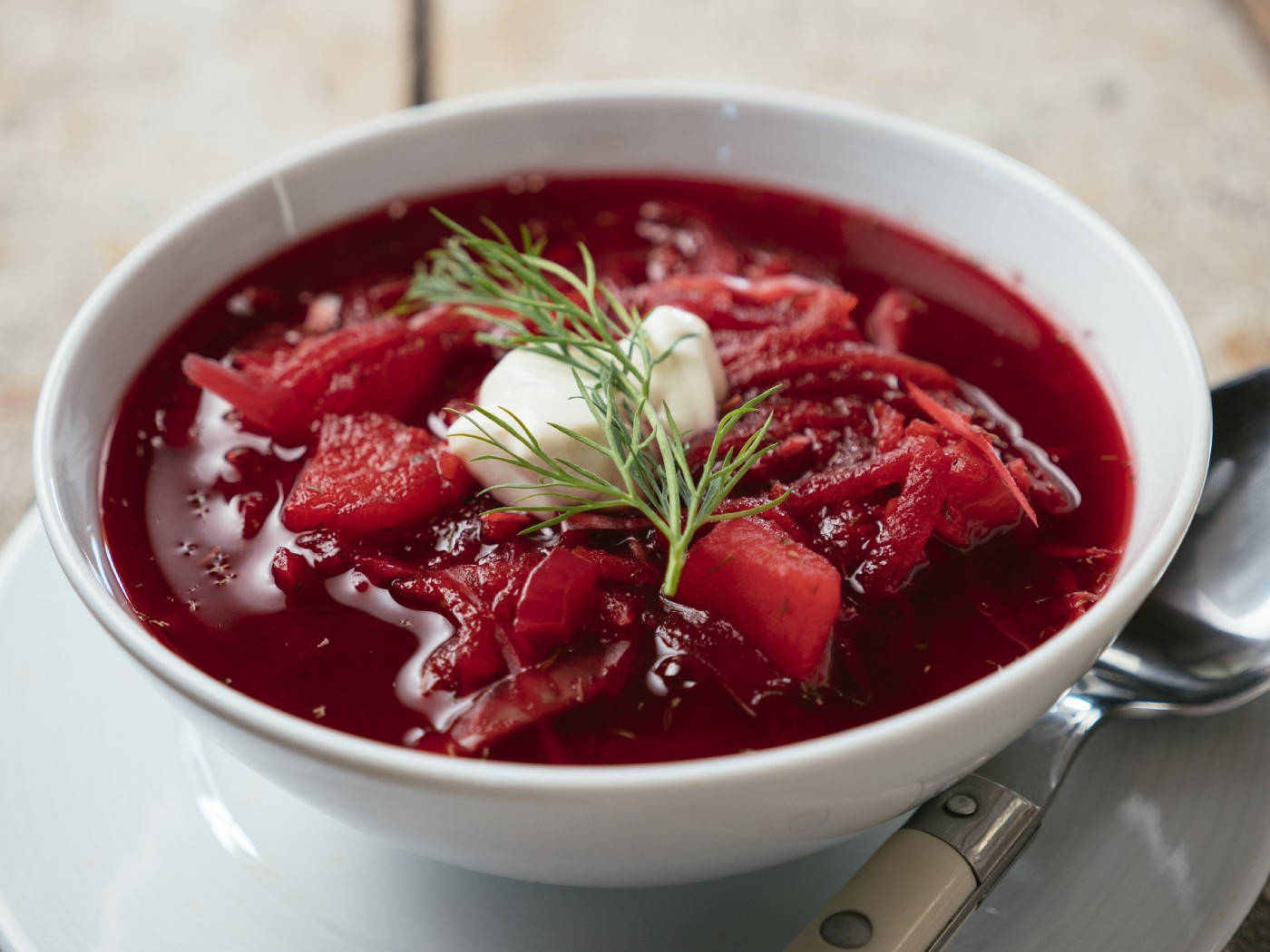 beetroot 桌布 壁紙 — 一碗色彩鮮豔的羅宋湯，上面放有酸奶油和新鮮蒔蘿，放在盤子上，旁邊有一隻湯匙。