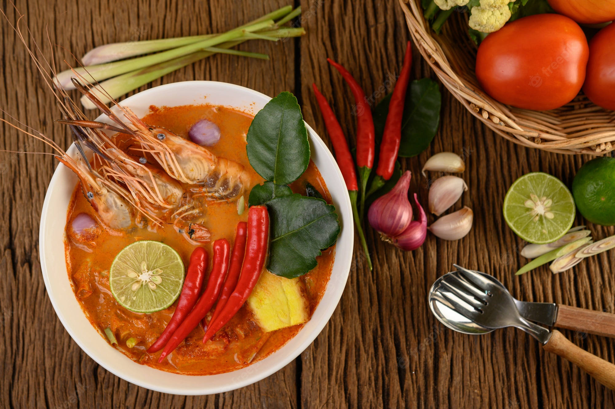 Food Photography 桌布 壁紙 — 一碗色彩鮮豔的辣味蝦咖哩，飾以青檸、辣椒和香草，放在鋪滿新鮮食材的鄉村風格木桌上。