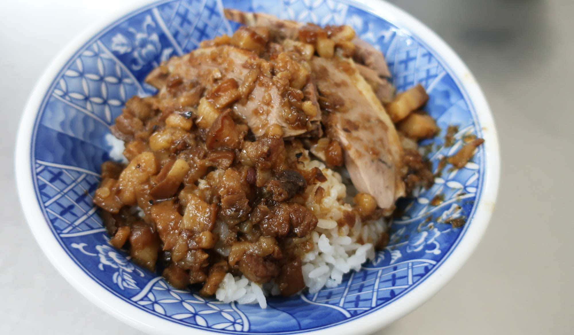 Food Photography 桌布 壁紙 — 一碗藍白圖案陶瓷碗中的燉豬肉飯的特寫。