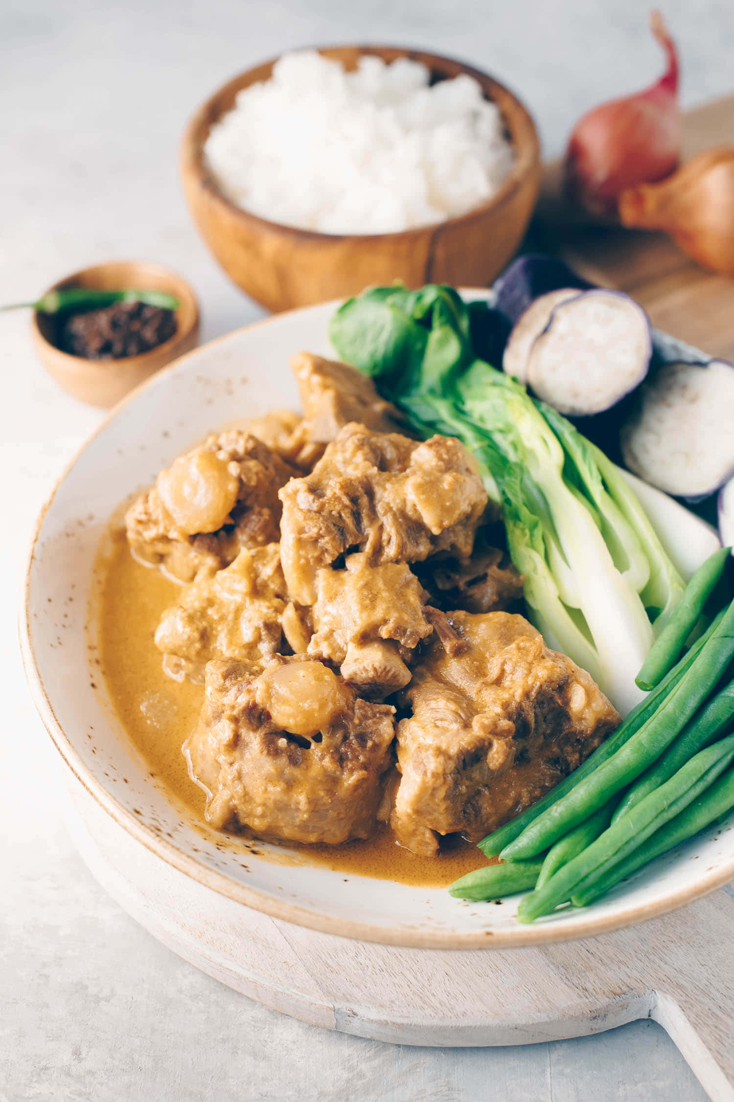 meat 桌布 壁紙 — 一碗豐盛的濃郁咖哩，配上嫩肉和鮮綠蔬菜，旁邊是蒸米飯和新鮮洋蔥。